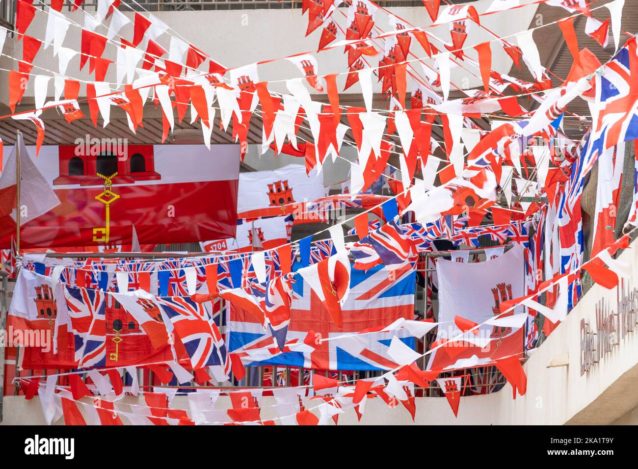 Lots of red and white bunting with national flags hanging across the staircase of an apartment block in Gibraltar. Stock Photo