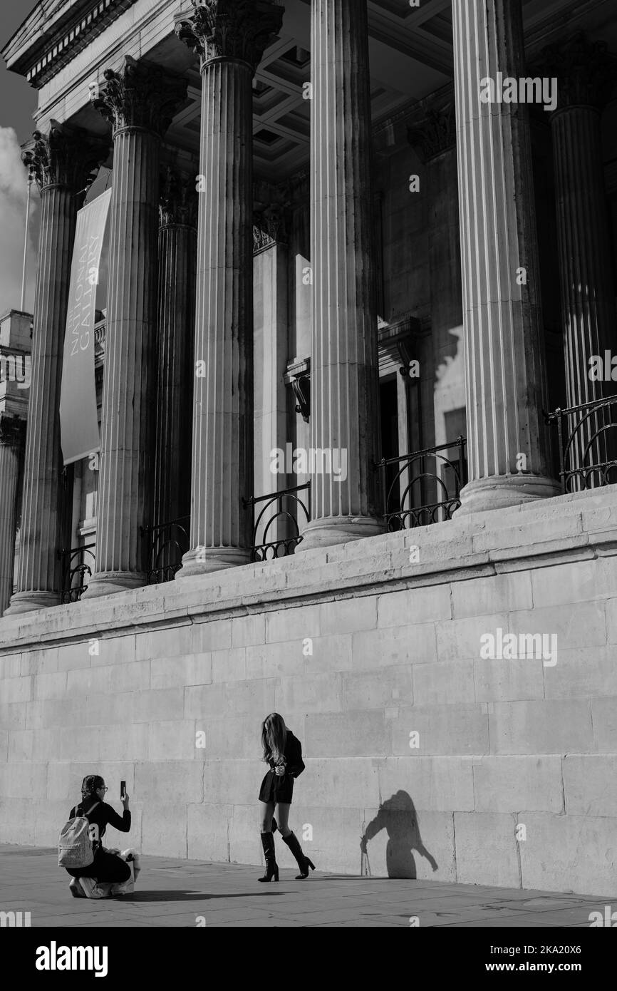 A young woman in a short skirt and high boots poses outside the National gallery in London. Stock Photo