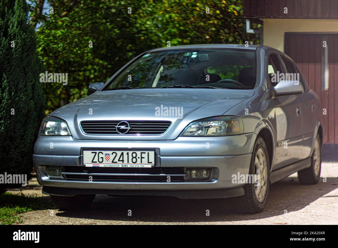 Silver Blue 2002 Opel Vauxhall Astra parked in front of home garage on sunny day exterior Stock Photo