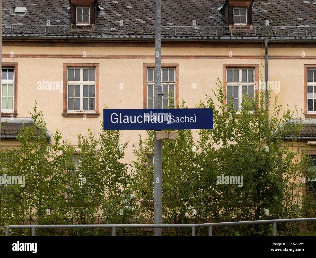 Name board of the train station in Glauchau, Saxony. The blue metal plate with white letters. Traveling by the public transportation service. Stock Photo