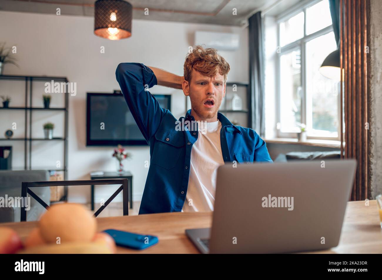 Ginger man reading something onlines and looking shocked Stock Photo