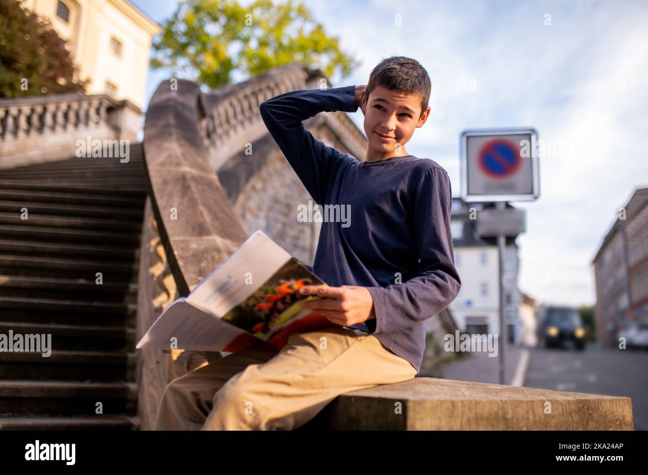 Teen with a book sitting on the concrete stairs balustrade Stock Photo ...