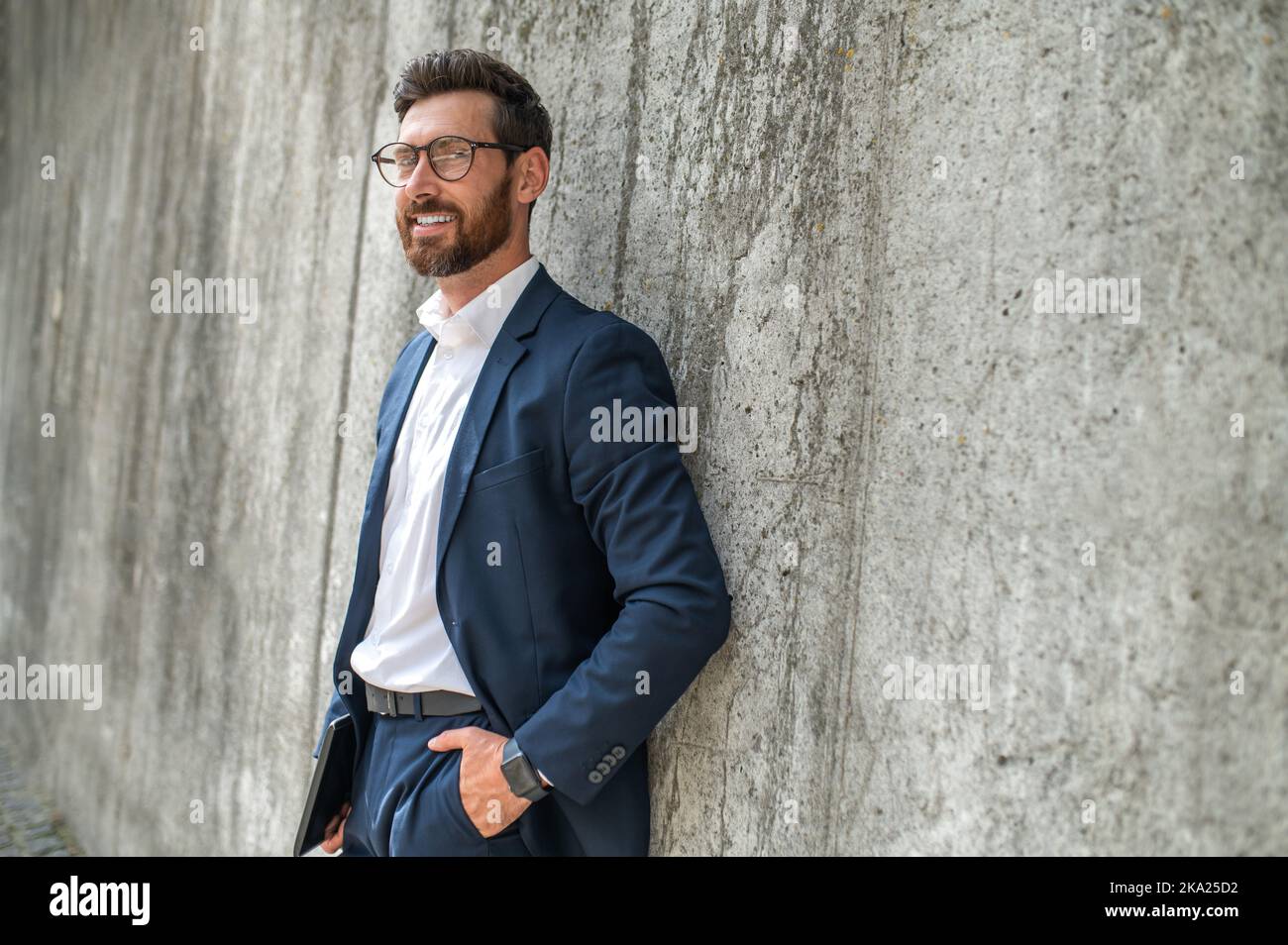 One man in a suit standing near the grey wall Stock Photo - Alamy