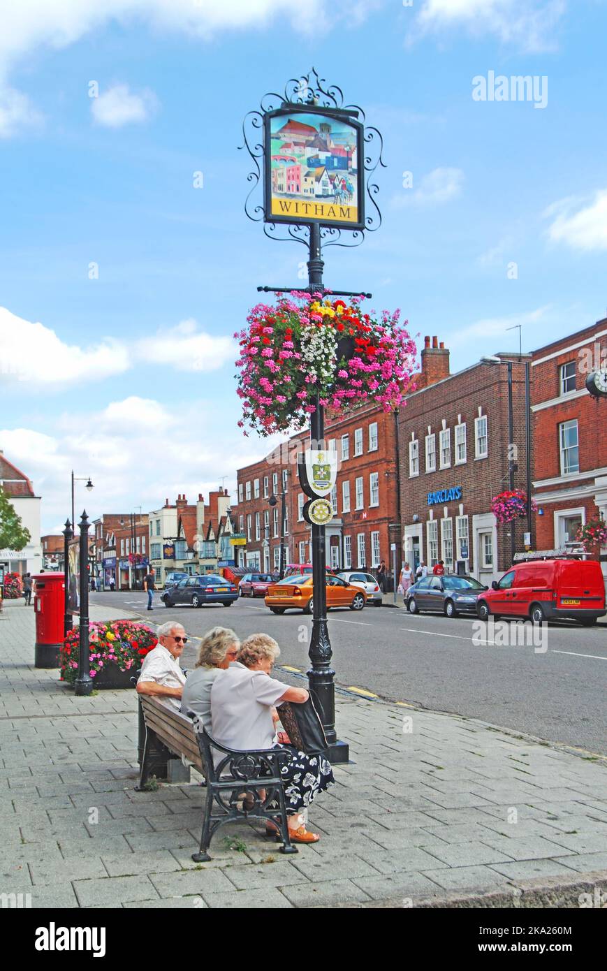 Witham town centre Newland Street sign & historical features colourful summer flowers hanging basket floral display people relaxing Essex England UK Stock Photo