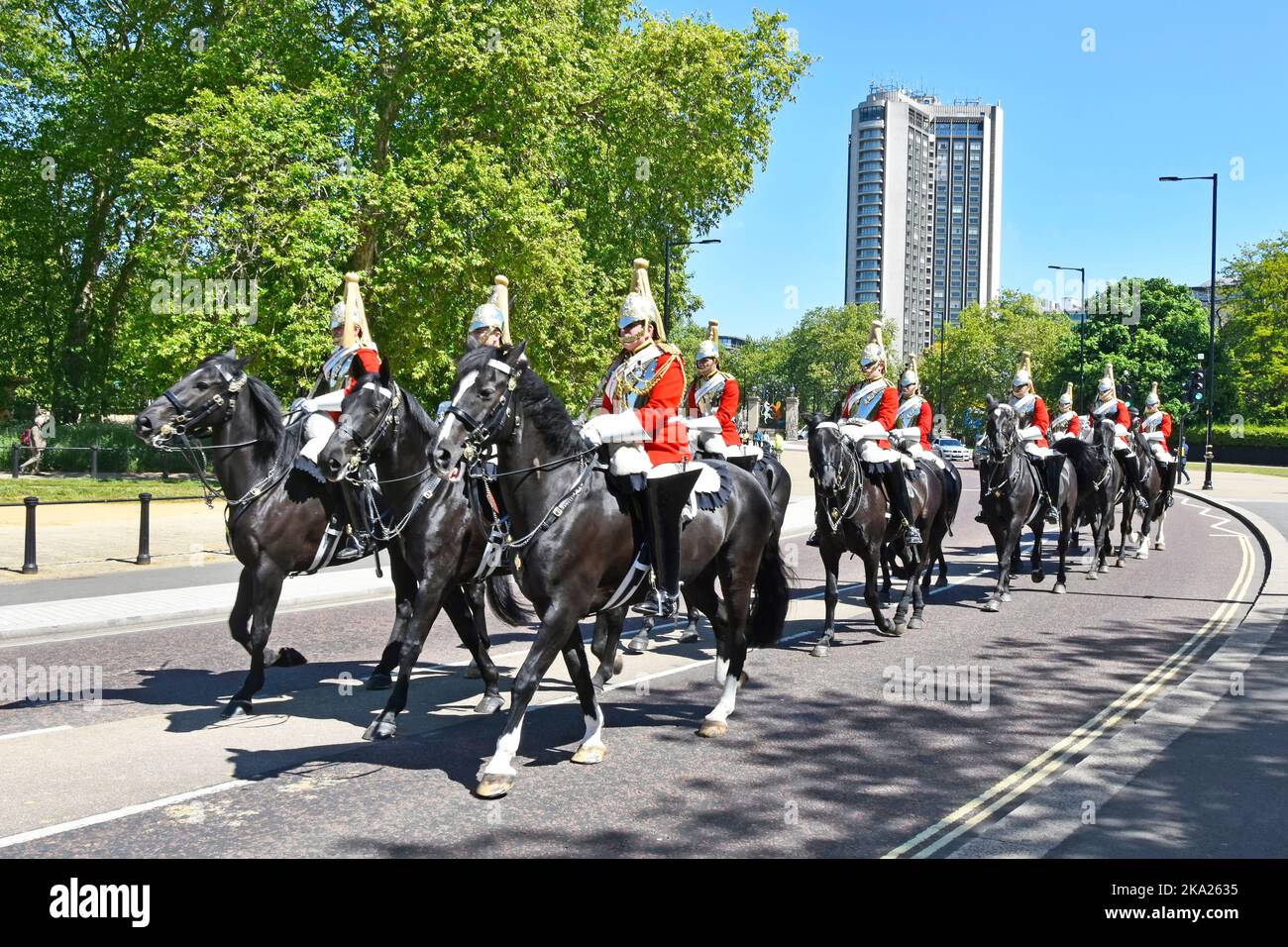 Hilton Hotel backdrop soldiers & horses of The Life Guards Household Cavalry Mounted Regiment in Hyde Park returning to barracks London England UK Stock Photo
