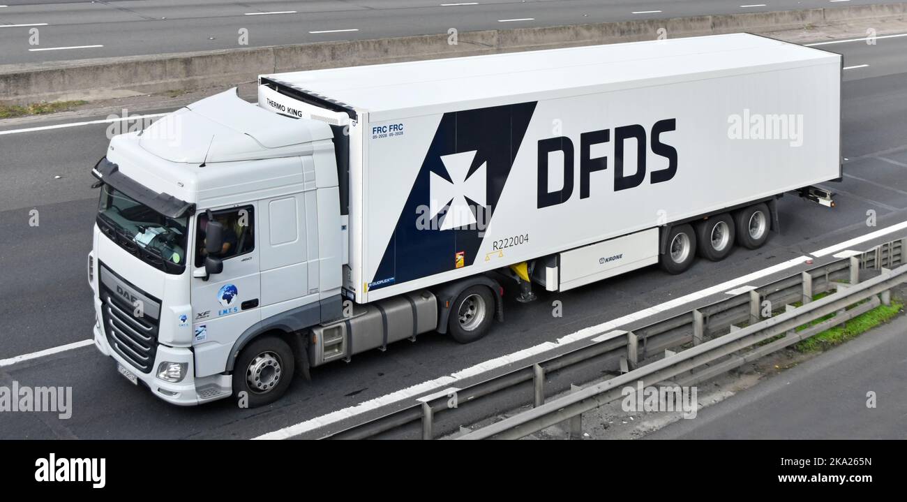 Close up side & front aerial view DAF XF hgv lorry truck driver tows DFDS articulated trailer a white commercial vehicle combination driving UK road Stock Photo