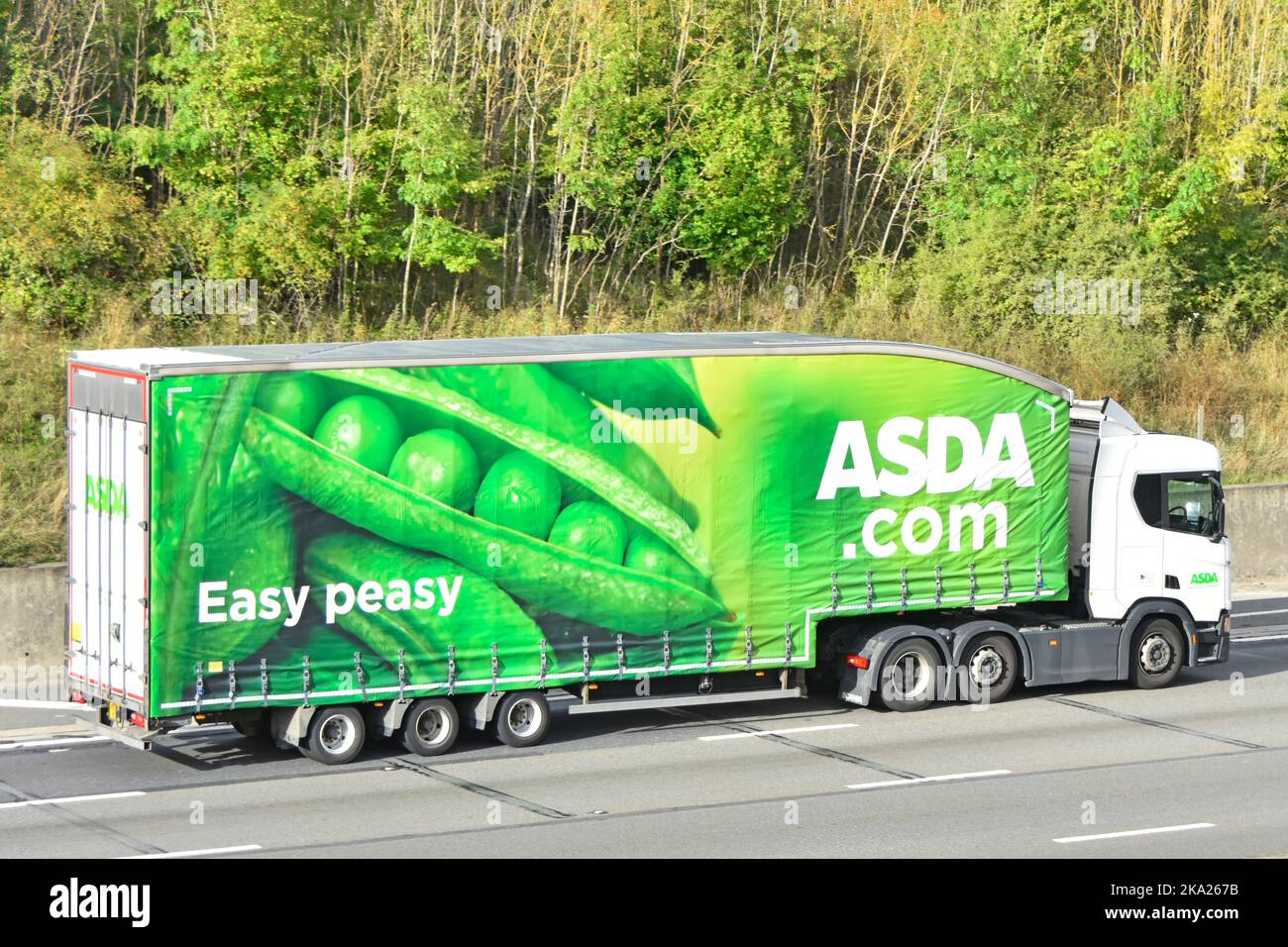 Easy peasy Asda supermarket Scania hgv lorry truck & green pea pod advertising graphic side curtain view articulated trailer driving UK motorway road Stock Photo