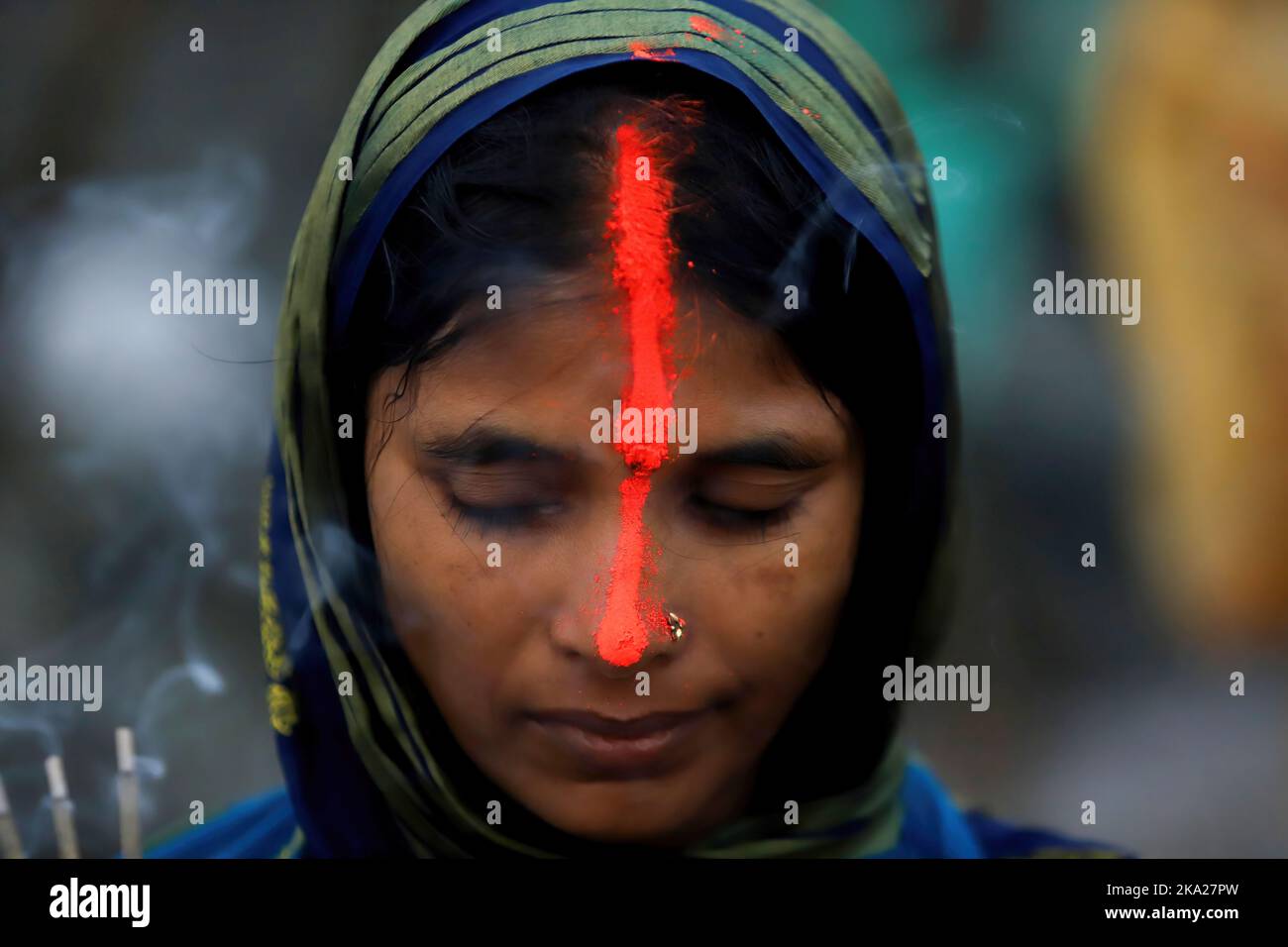A devotee with vermilion on her face performs Chhath Puja rituals as