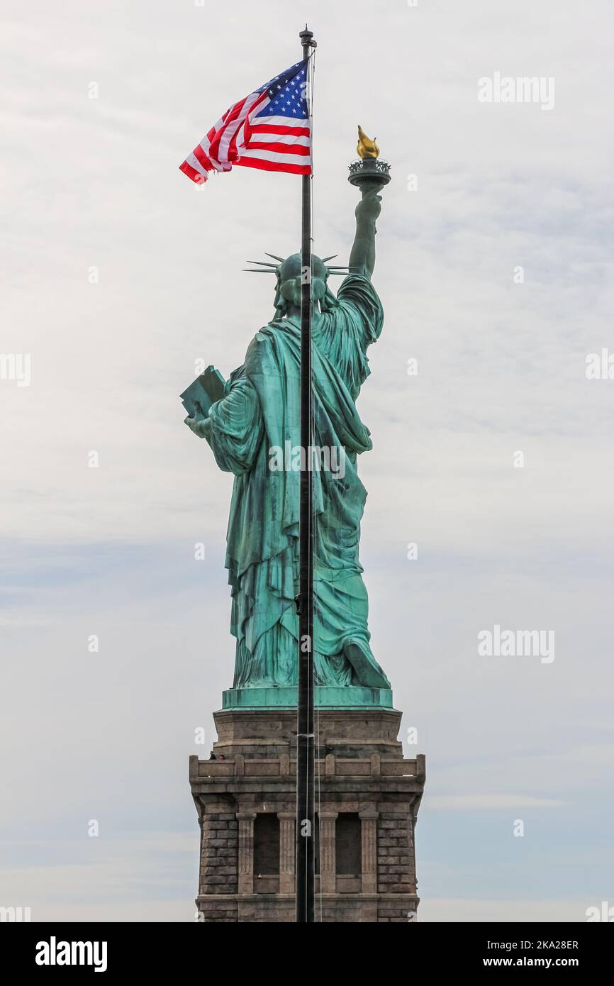 Back view of Liberty Statue with stars and stripes flag waving Stock Photo