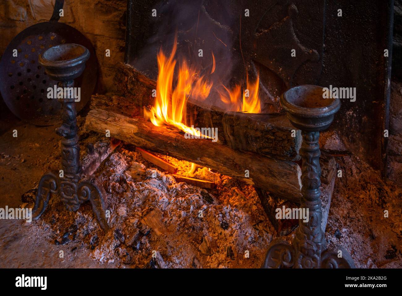 A close up of wood logs burning on a typical hearth fire, with metal fireside ornaments. Stock Photo