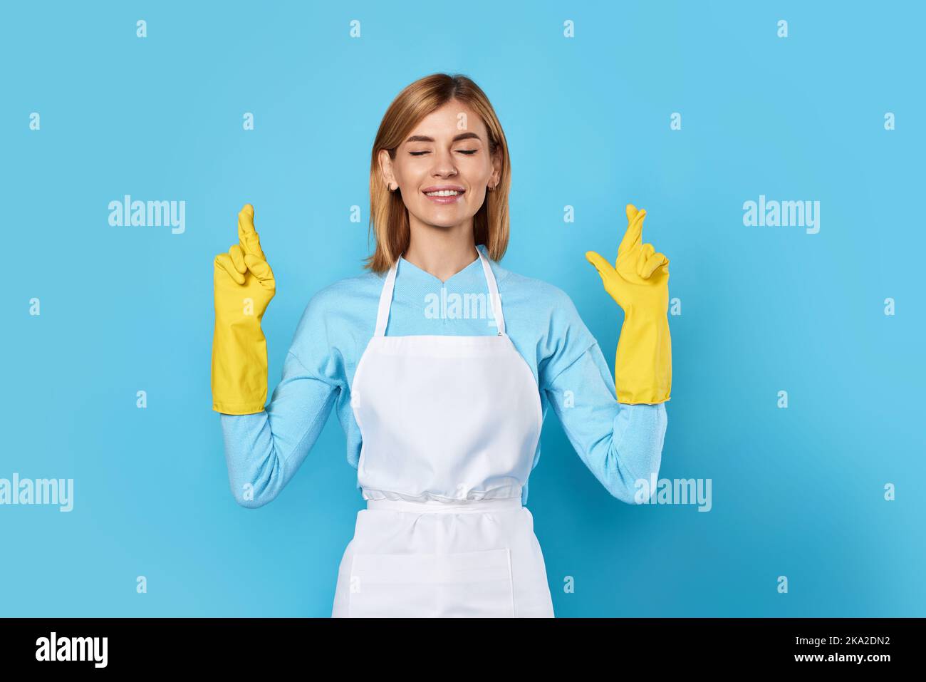 woman in rubber gloves with finger crossed gesture Stock Photo - Alamy
