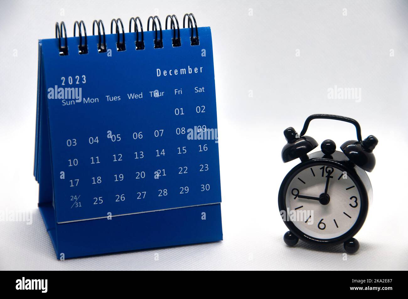 Alarm clock pointing at 9 o'clock with December 2023 calendar on white background. Time and calendar concept. Stock Photo