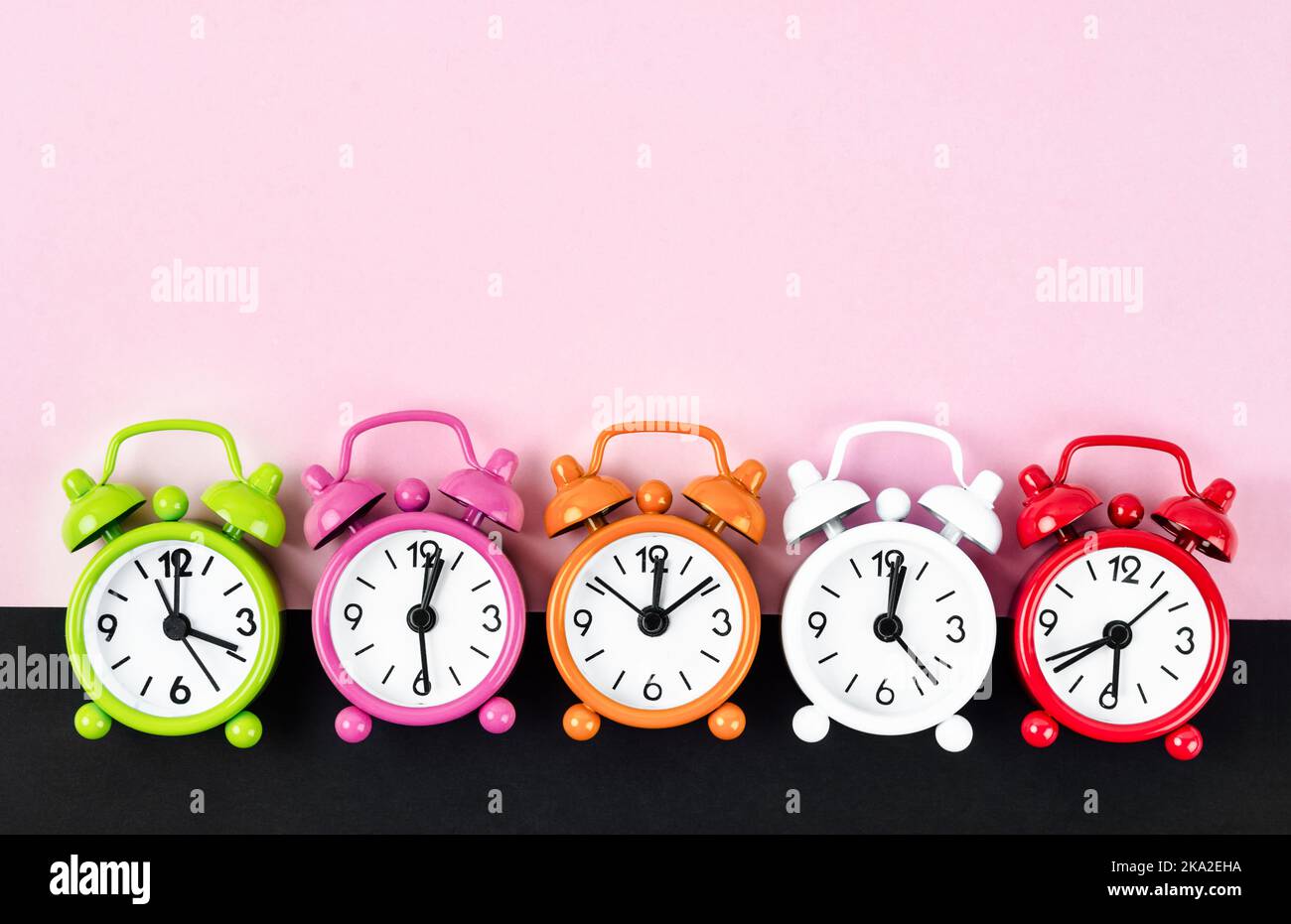 Many different alarm clocks on pink colour background with copy space
