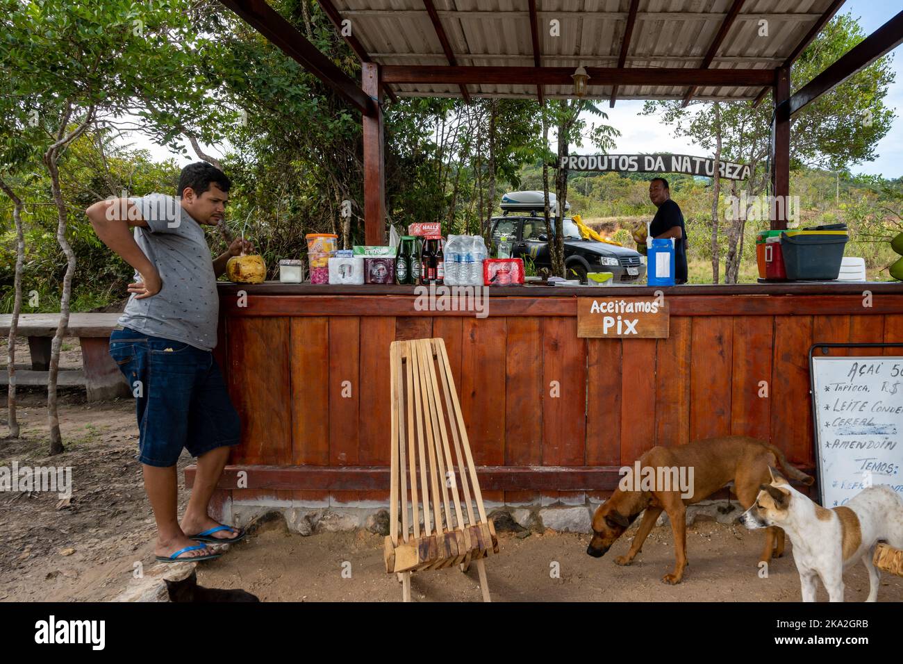 A man selling snacks and cold drinks at a roadside stand. Tepequém, Roraima State, Brazil. Stock Photo