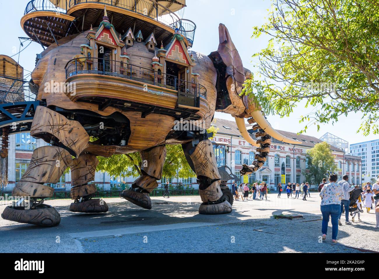 The Great Elephant giant puppet, part of the Machines of the Isle of Nantes tourist attraction, wanders amid onlookers along the shipyards building. Stock Photo