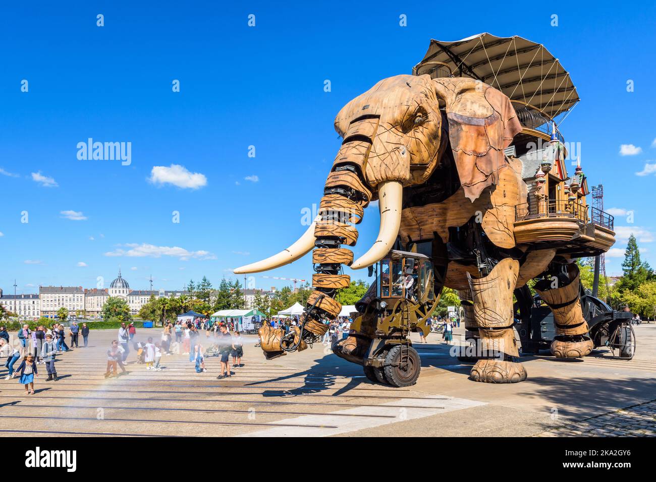 The Great Elephant giant puppet, part of the Machines of the Isle of Nantes tourist attraction, sprays water with its trunk on excited children. Stock Photo