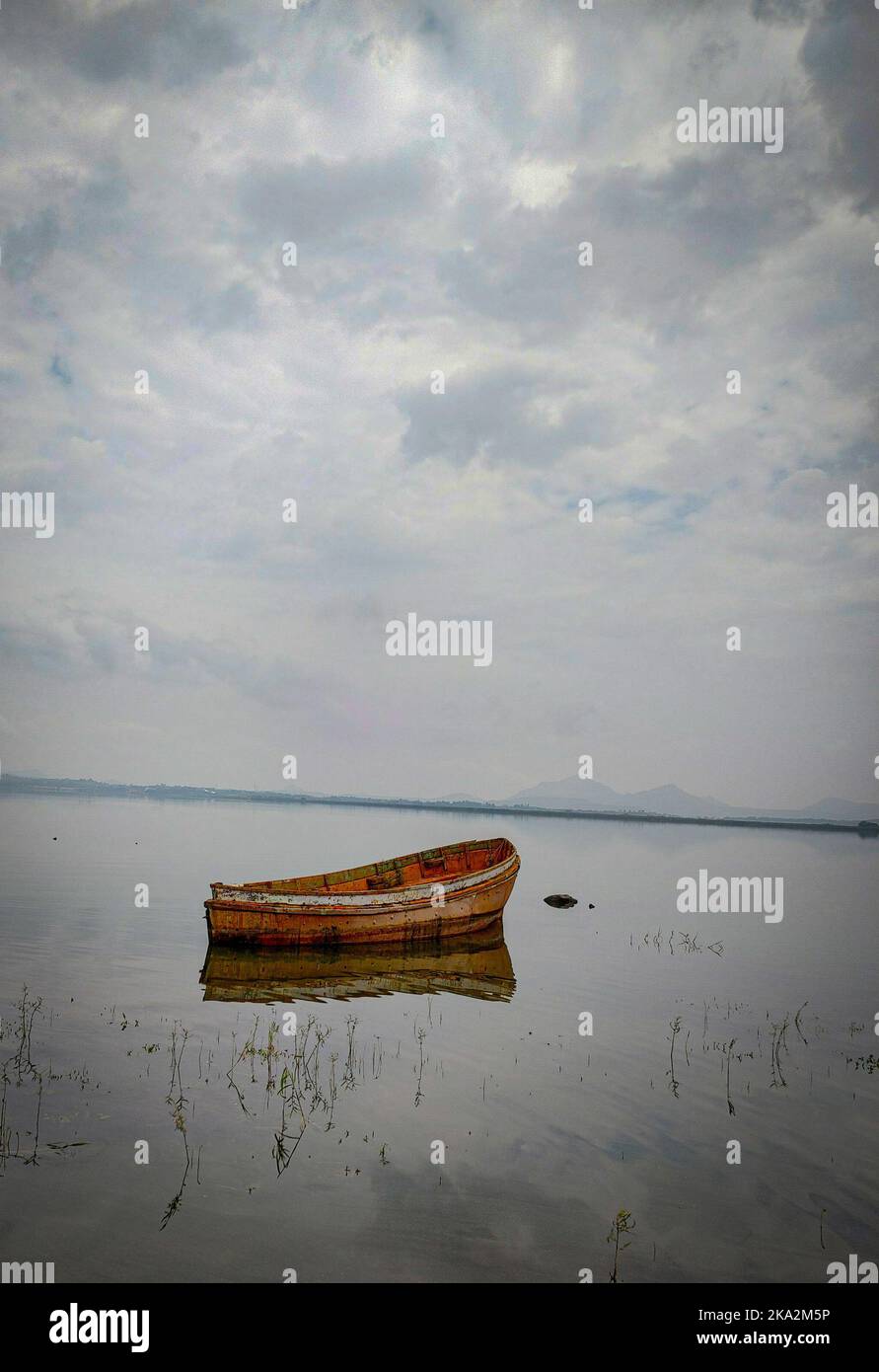 An unmanned wooden boat floating on a calm lake Stock Photo - Alamy