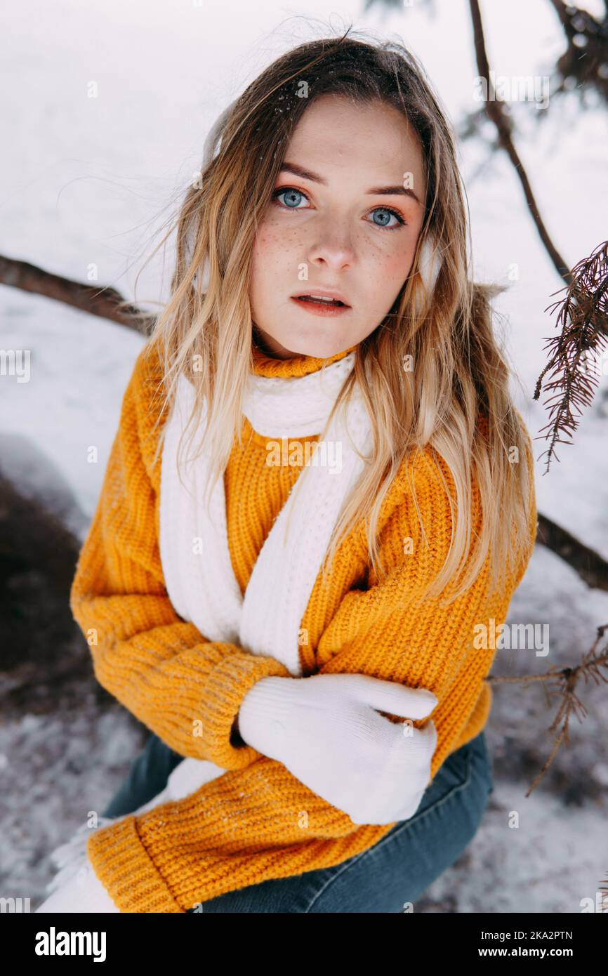 Teen blonde in a yellow sweater outside in winter. A teenage girl on a walk in winter clothes in