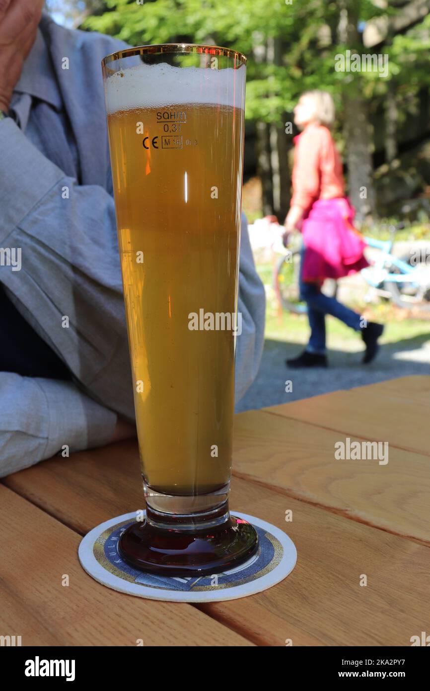 Weißbier Weizen in ein modern geformtes Glas eingeschenkt, aufgenommen im Sommer in einem Biergarten Stock Photo