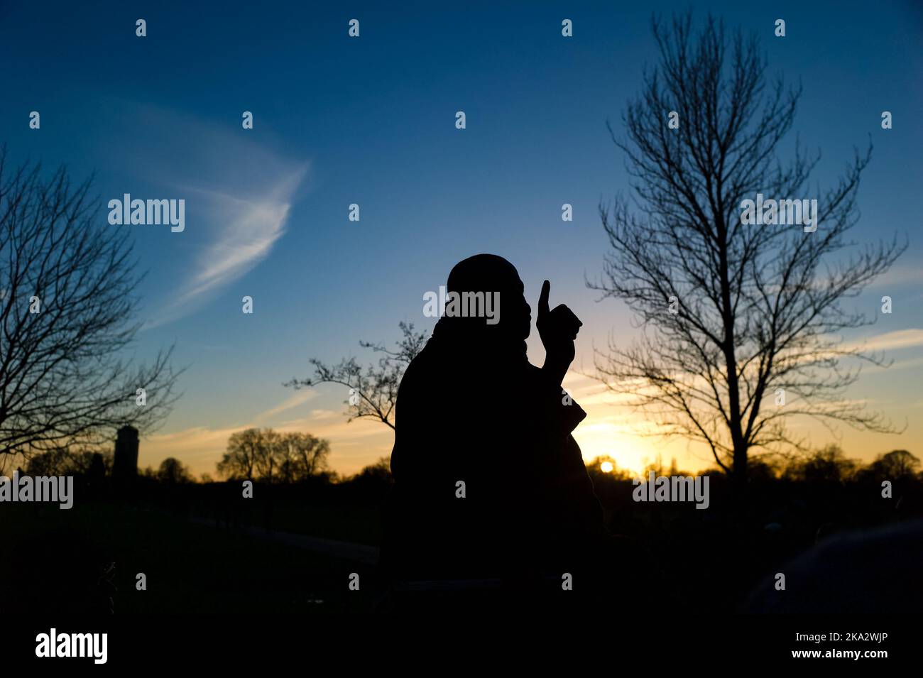 A man stands silhouetted at sunset whilst making a speech at Speakers Corner, London, UK. Stock Photo