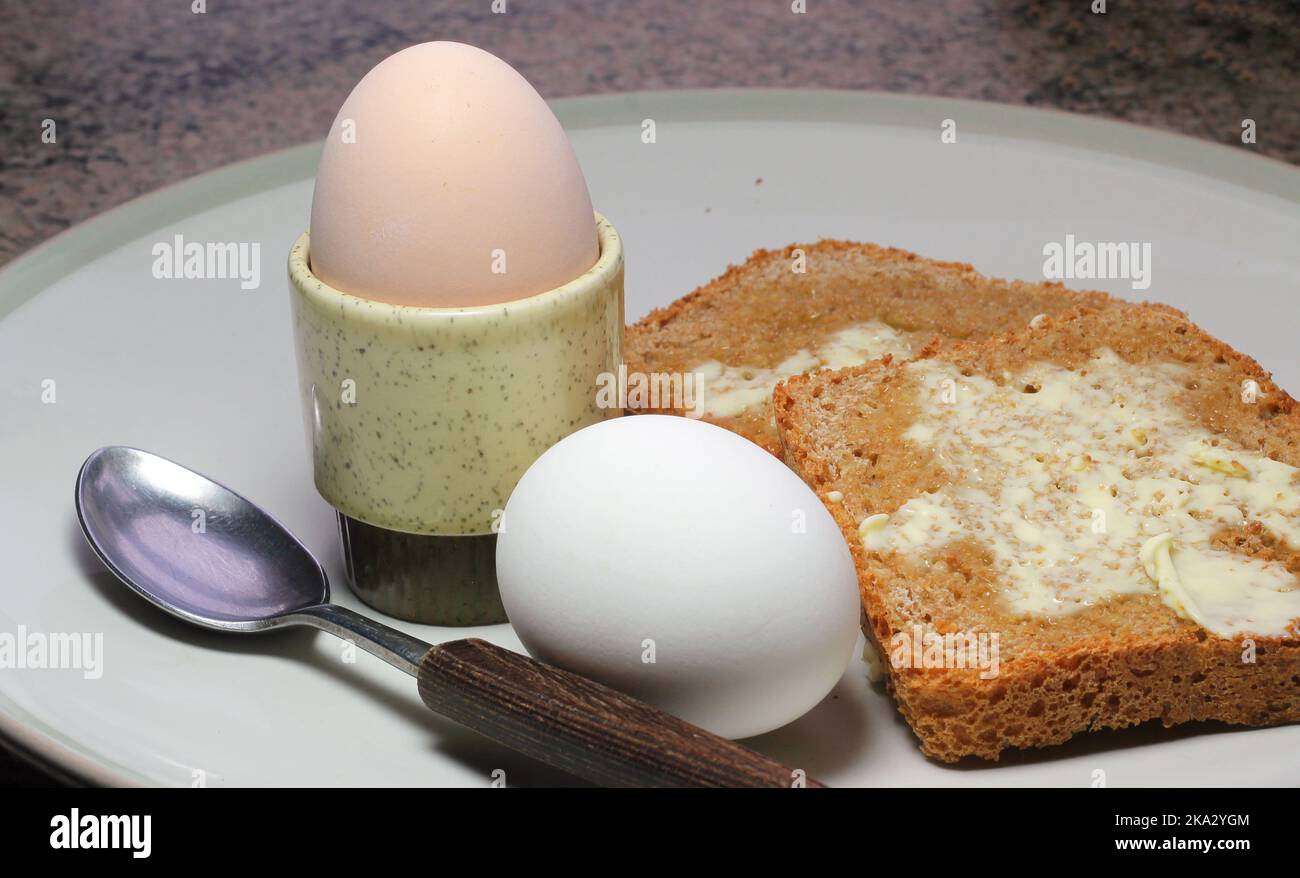 Two boiled eggs. One egg in a an egg cup. Toast on the plate. Breakfast. Stock Photo