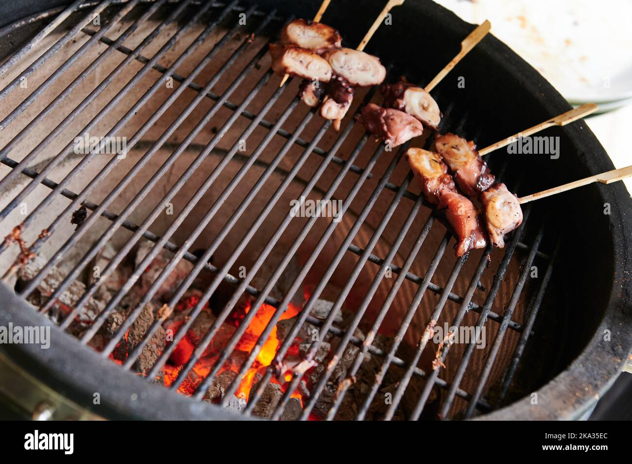 Barbecue with glowing embers and octopus skewers Stock Photo Alamy