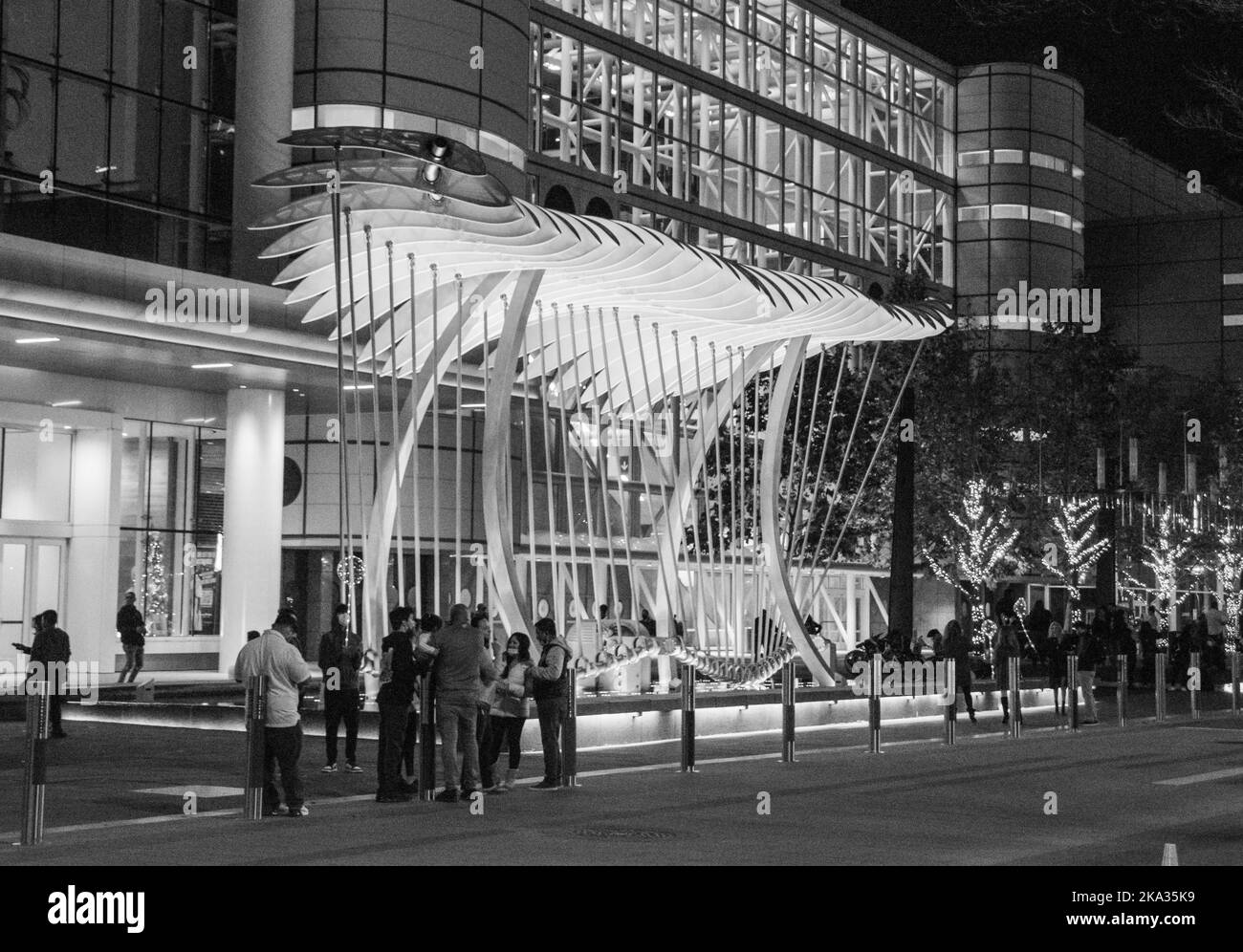 A grayscale shot of a sculpture of wings over water in downtown
