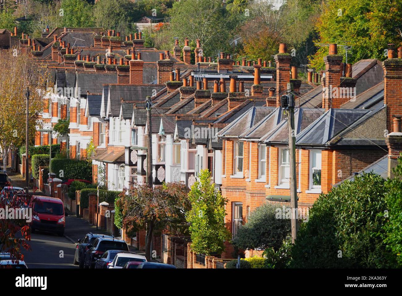 Street of brick victorian terrace houses with numerous chimneys in leafy English suburb on sunny autumn day. Stock Photo