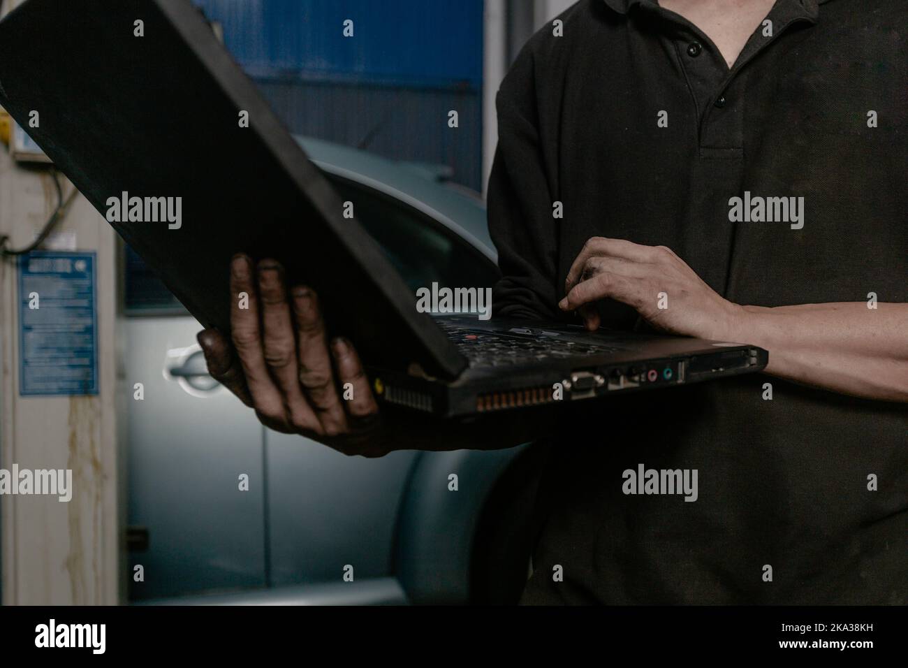 Car mechanic working on laptop in workshop Stock Photo