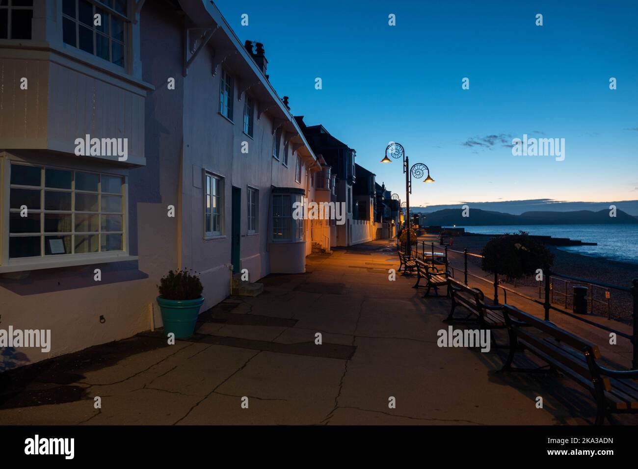 view of cottages along the promenade at Lyme REgis Dorset just before sunrise with the sea in the background Stock Photo