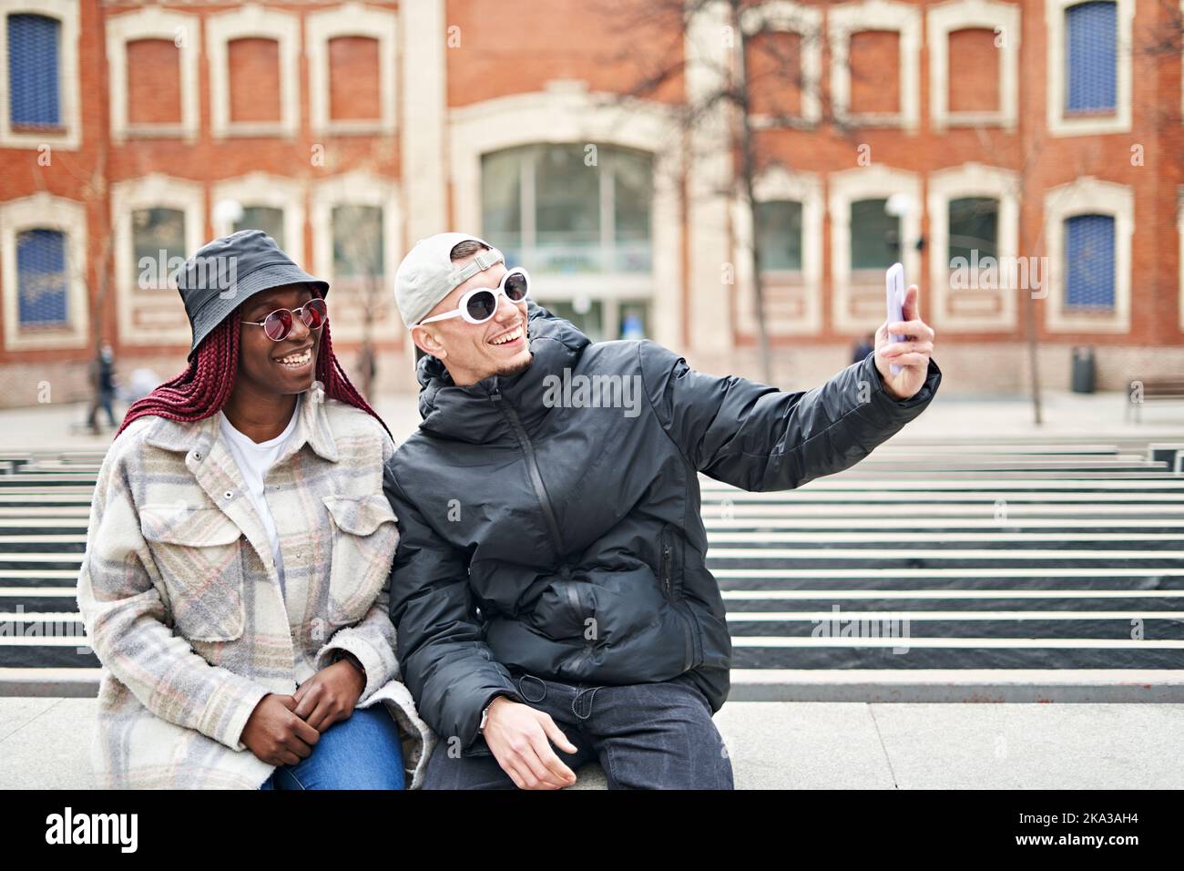 multiethnic couple using phone taking selfie, on the street Stock Photo