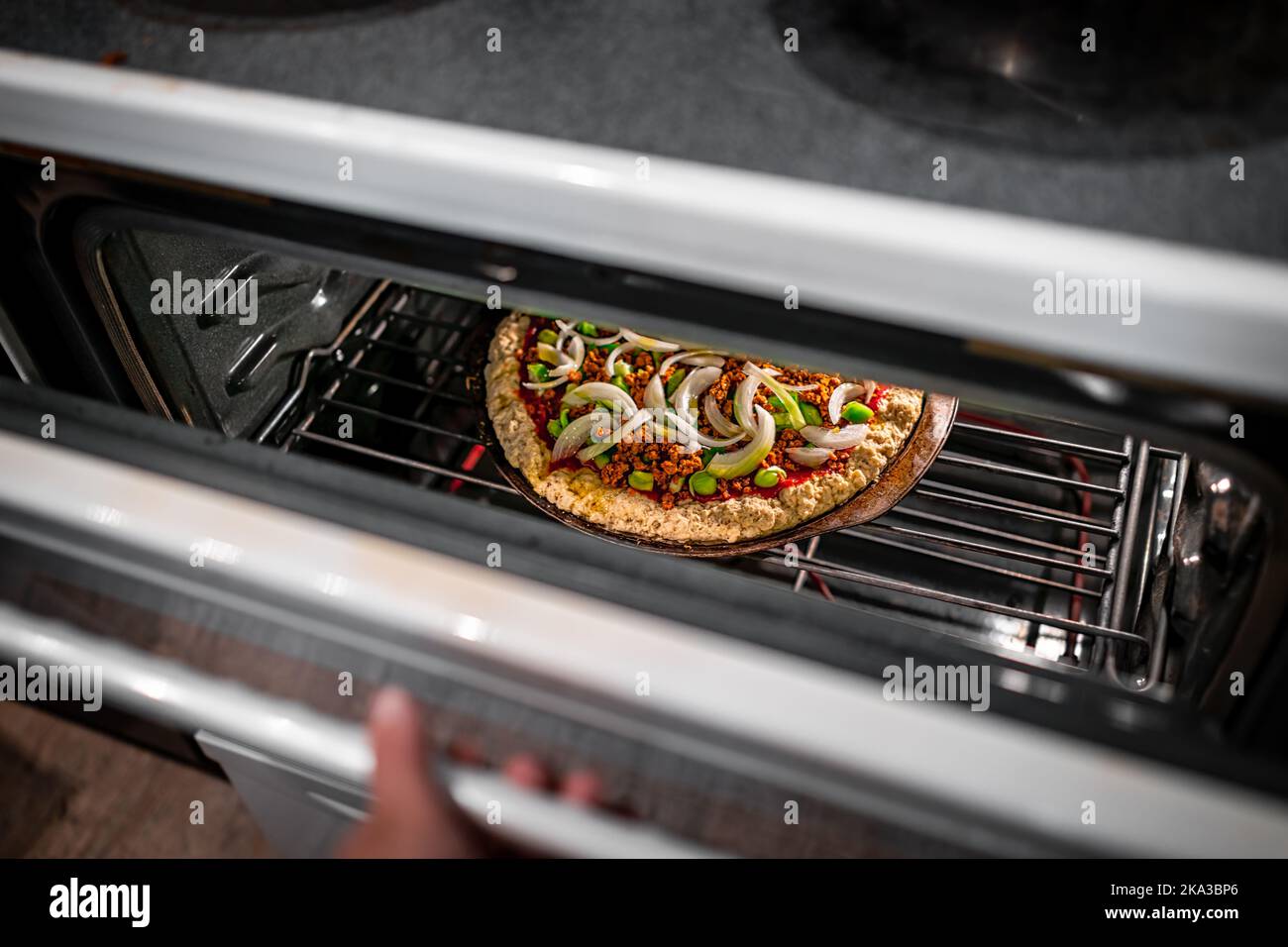 Hand opening oven door checking homemade pizza cooking baking with