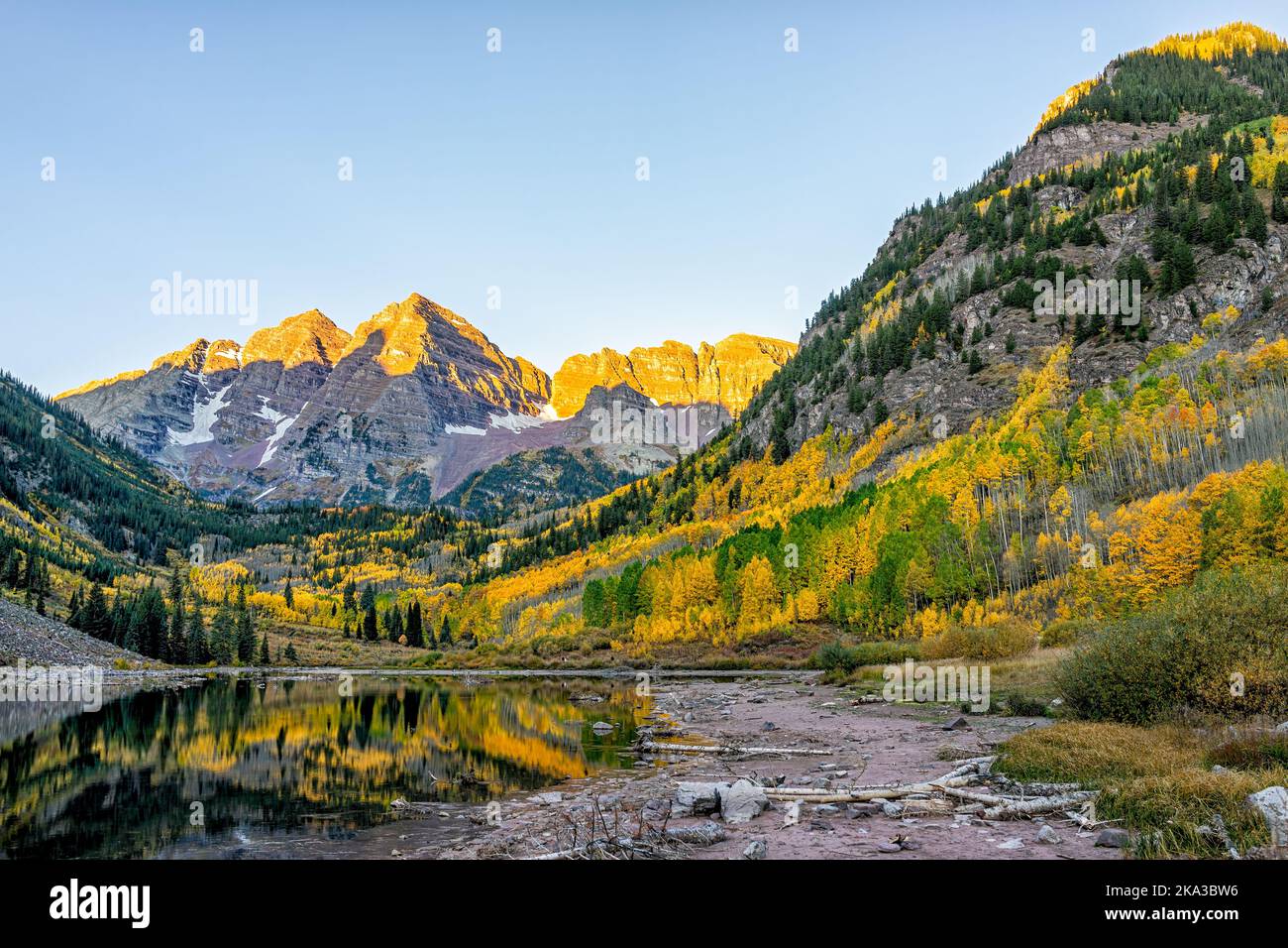 Maroon Bells lake at sunrise sunlight in Aspen, Colorado with rocky mountain peak and snow in October autumn and golden fall leaf color trees reflecti Stock Photo