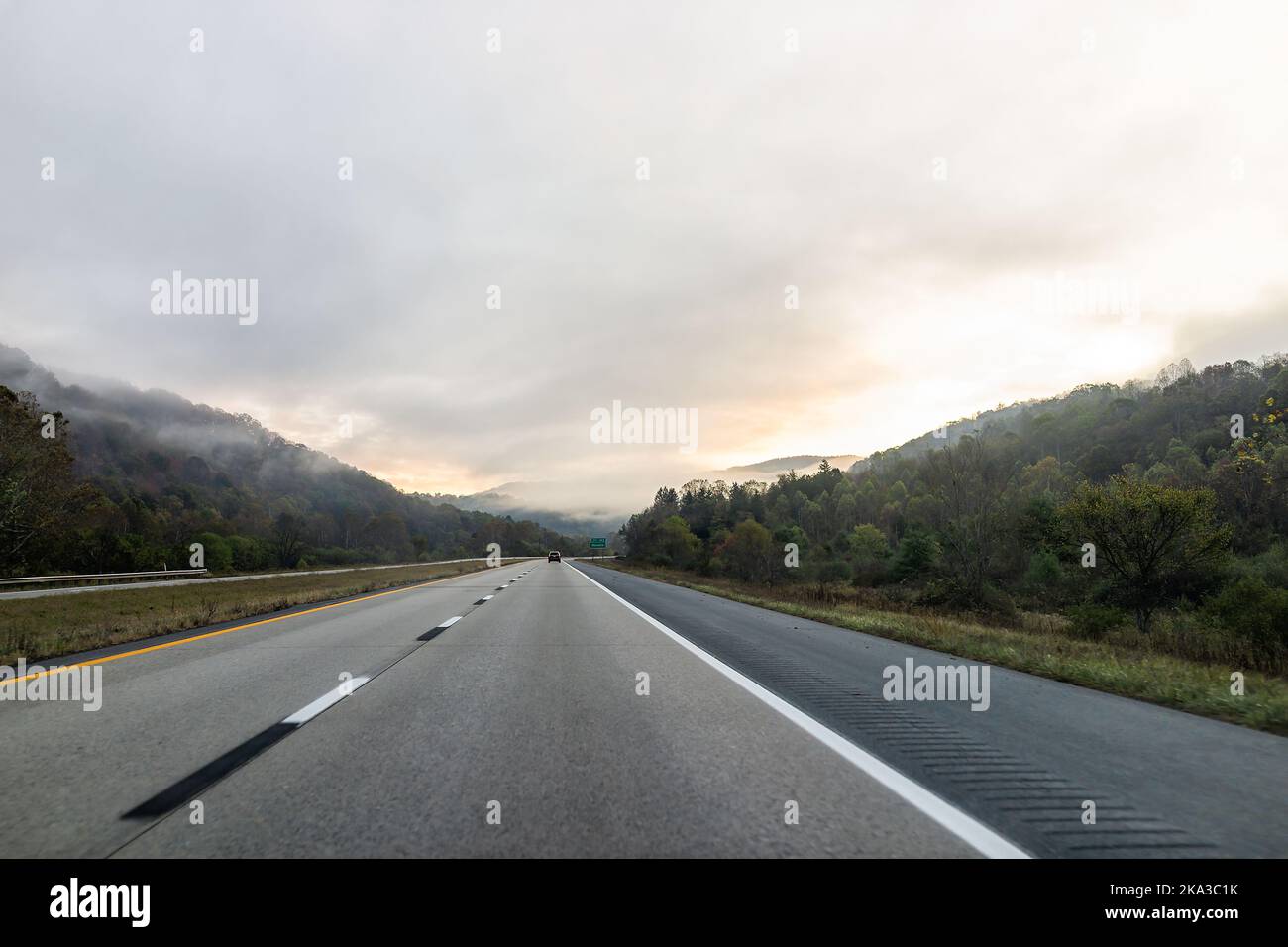 Fog mist weather in morning sunrise on road highway 64 driving in rural countryside in West Virginia with cars in traffic and sign for exit to Rainell Stock Photo