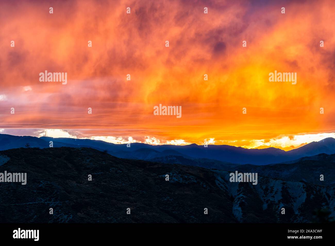 Aspen, Colorado rocky mountains range silhouette at vibrant colorful sunset of orange yellow sky light with clouds in cloudy sky Stock Photo