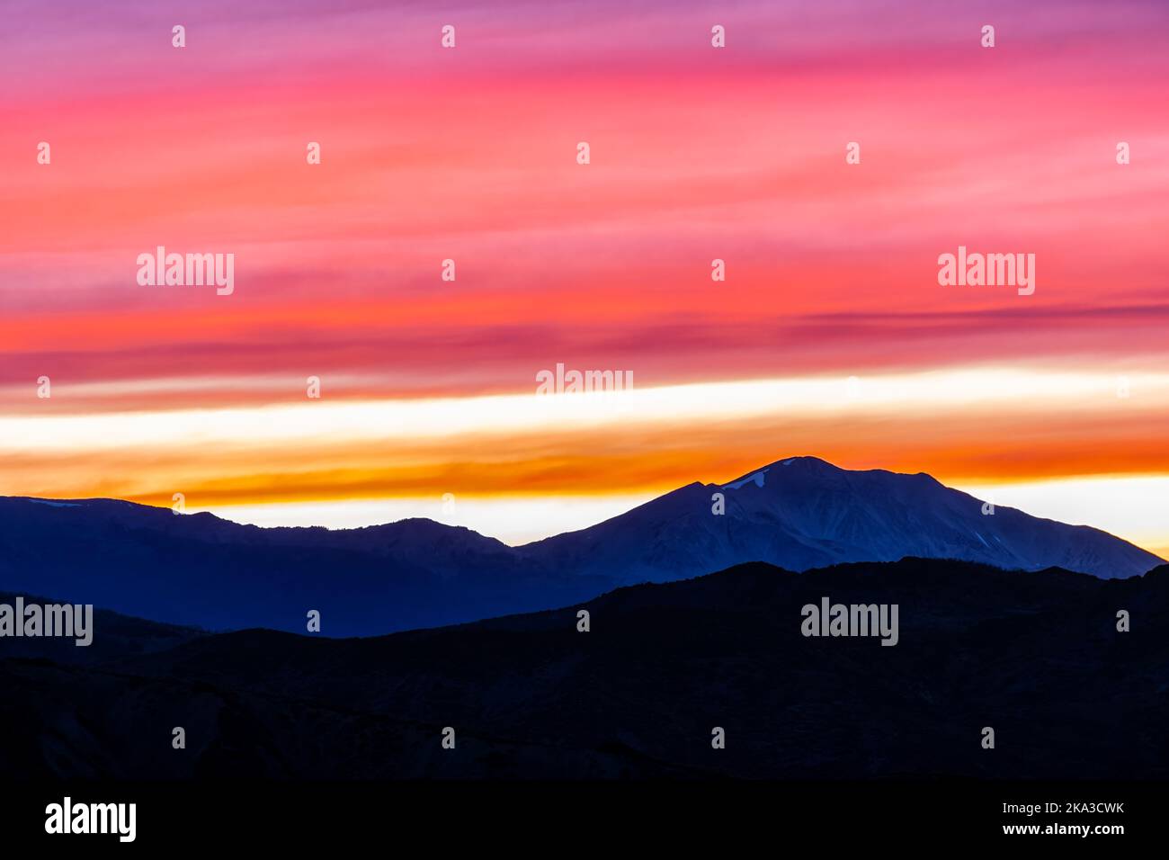 Orange red pink cloudy sunset in Aspen, Colorado with Rocky mountains peak range, vibrant color of clouds at twilight with mountain ridge silhouette Stock Photo