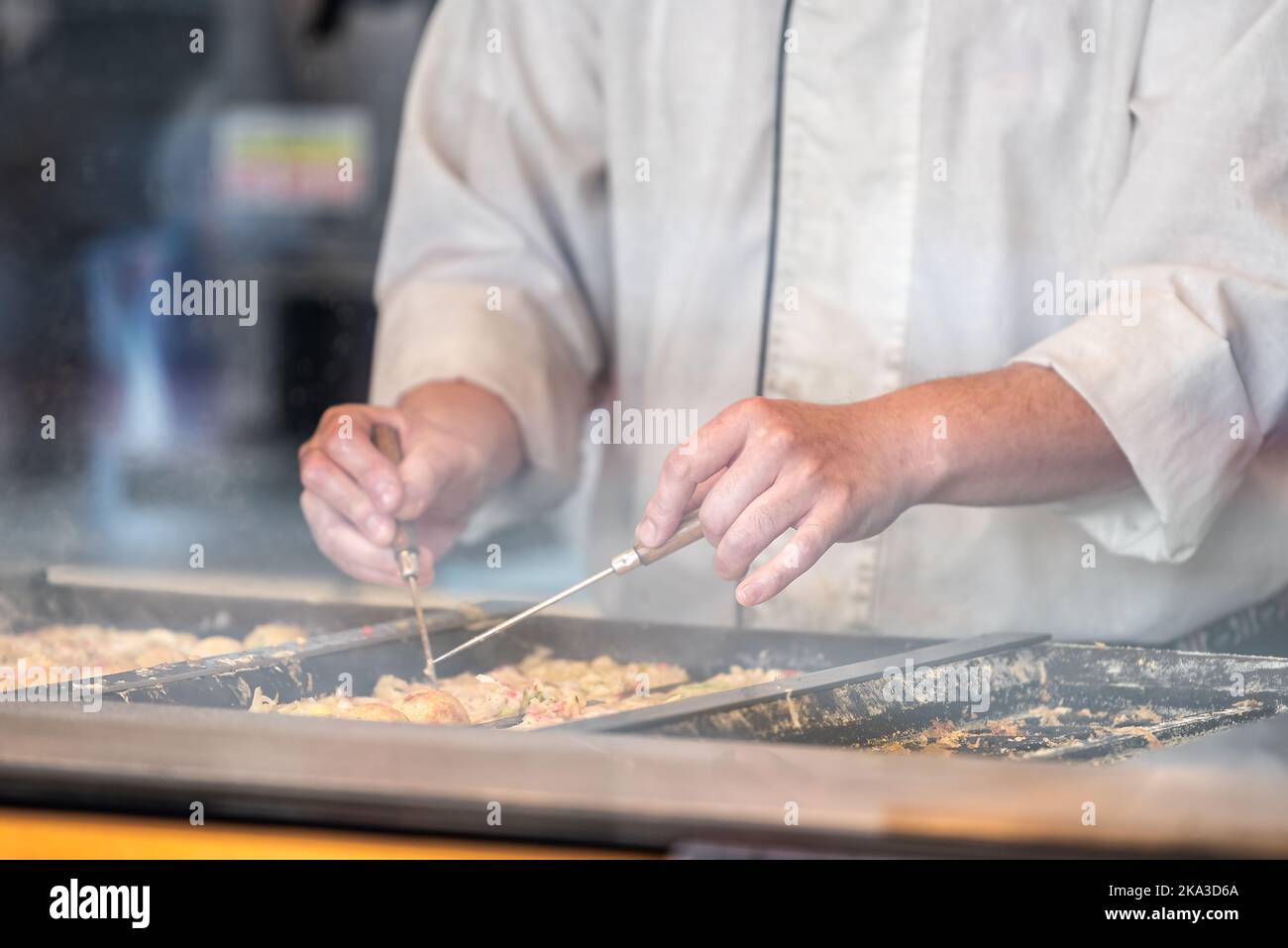 Closeup of man chef person cooking turning flipping over takoyaki