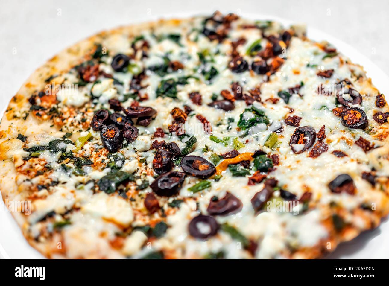 Macro closeup of cooked baked take and bake Greek feta cheese spinach mozzarella cheese pizza