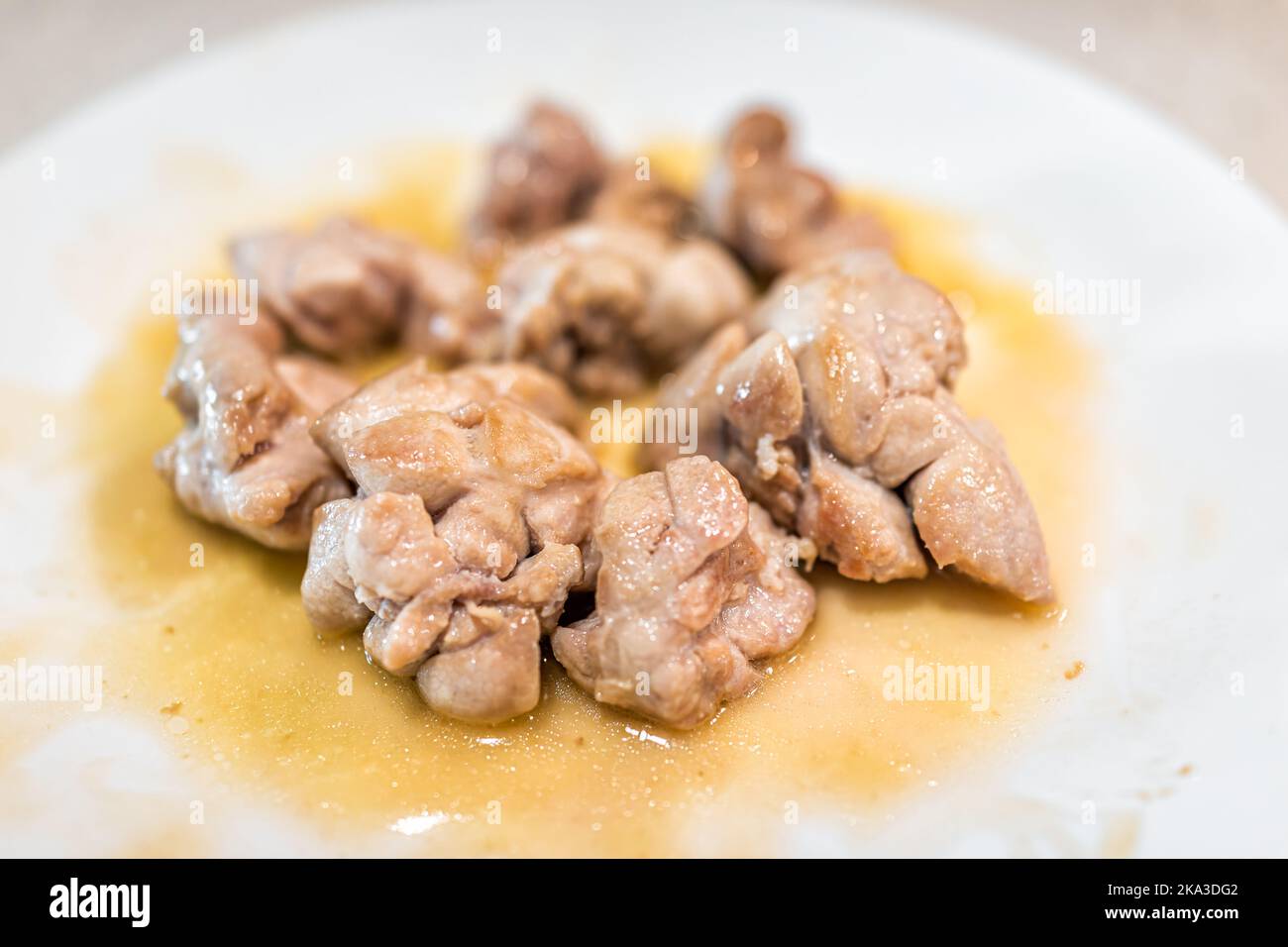 Macro closeup of fresh whole cooked fried beef sweetbreads thymus organ gland, nutritious ancestral meat homemade food on white plate on kitchen table Stock Photo