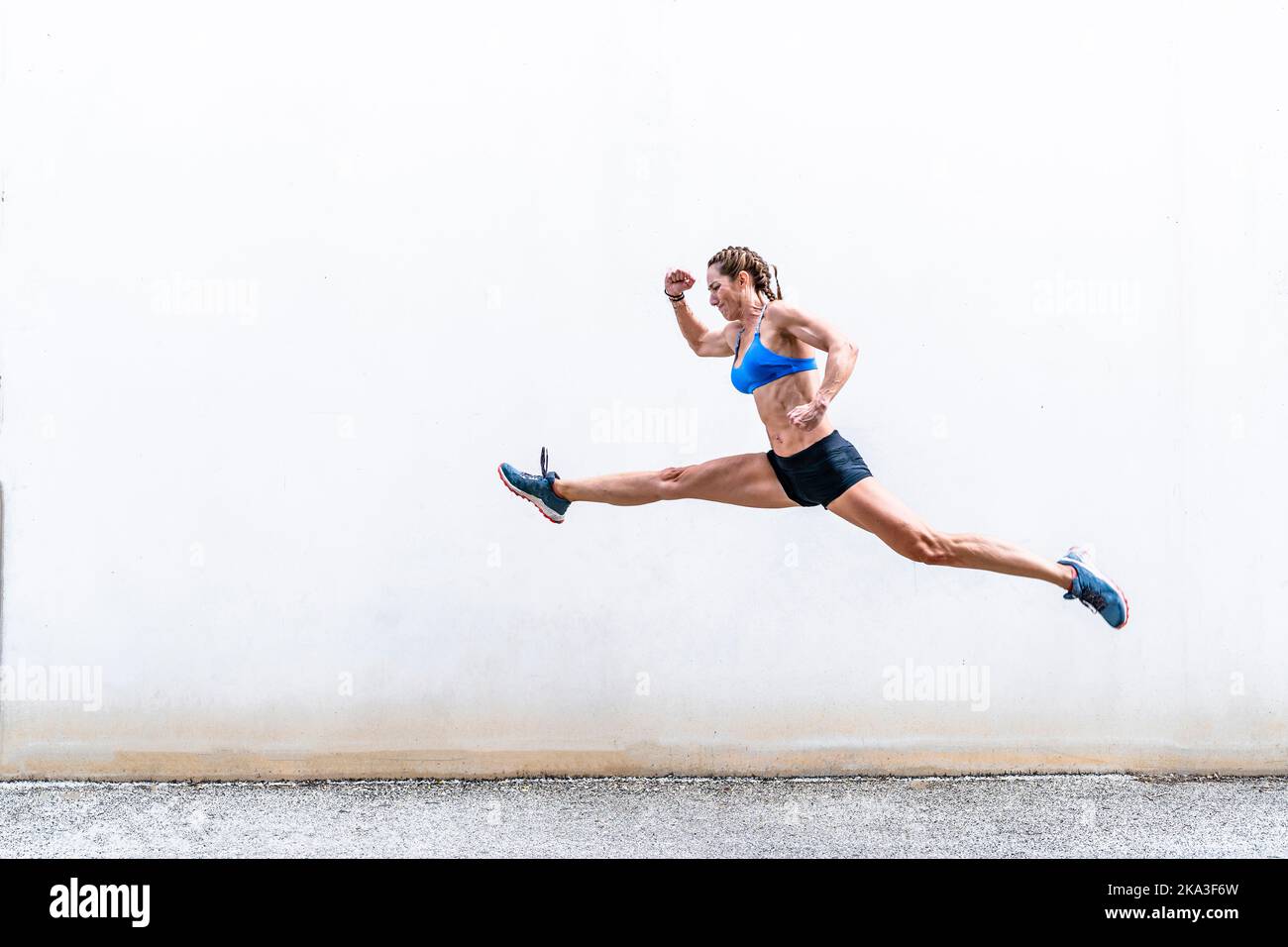 Full body determined muscular female athlete in activewear raising arm