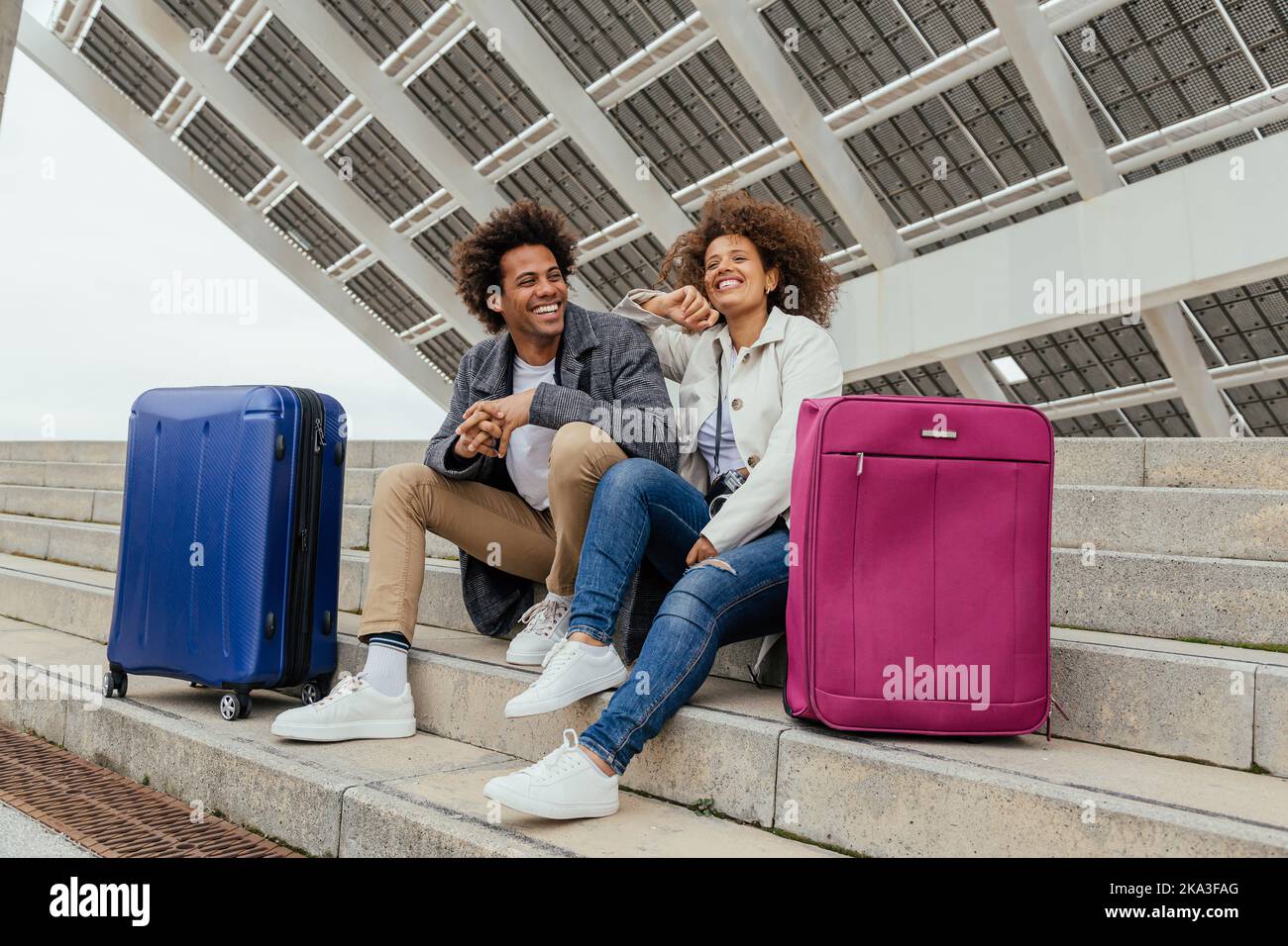 Low angle of cheerful African American couple in casual clothes sitting ...