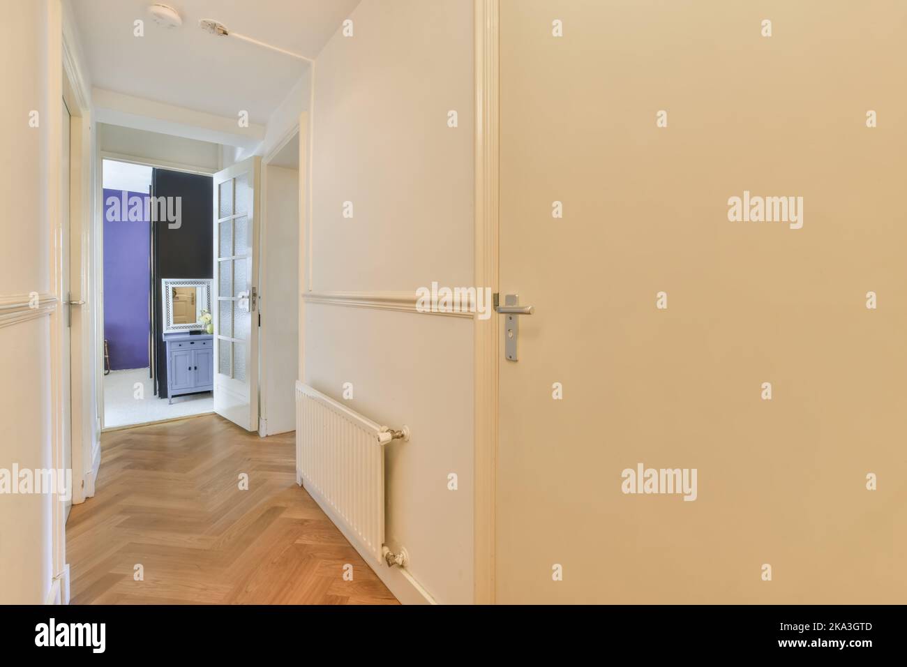 Hallway of modern apartment with white walls and doors and laminated flooring Stock Photo