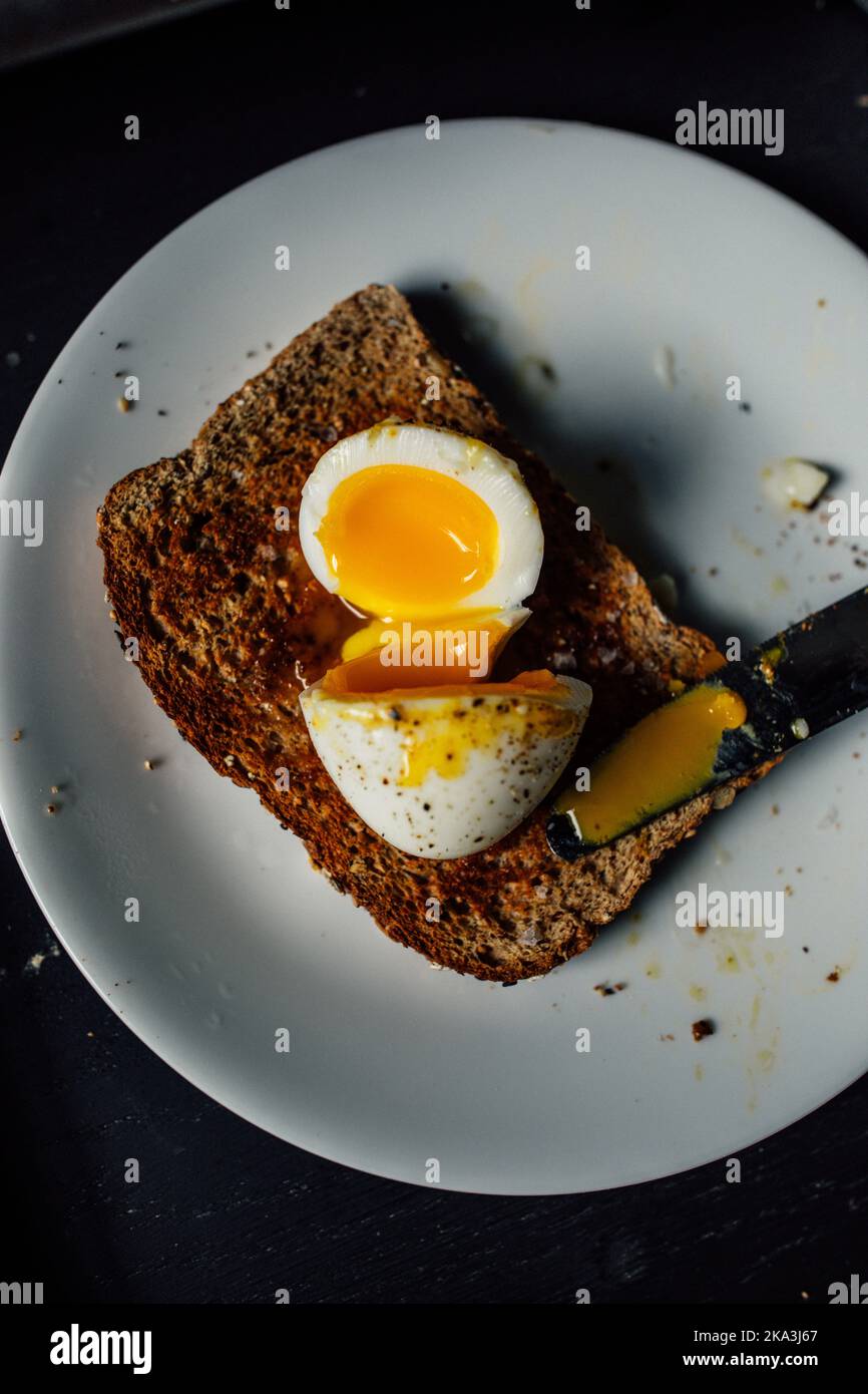 jammy soft boiled egg on whole wheat toast with salt, pepper, knife