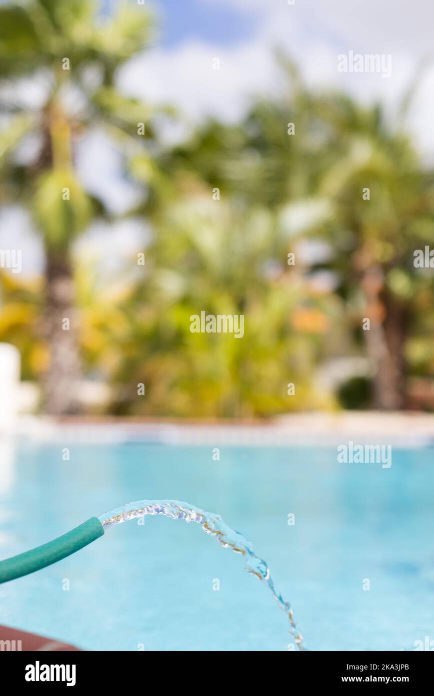 Water pipe filling up swimming pool with clean crystal water. Closeup