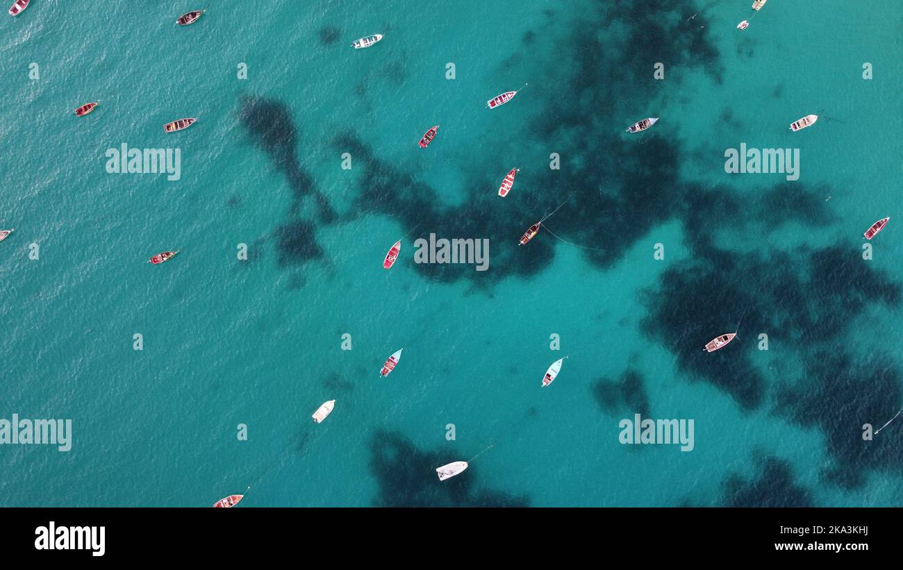 An aerial top view of many boats sailing in the turquoise seascape on a ...