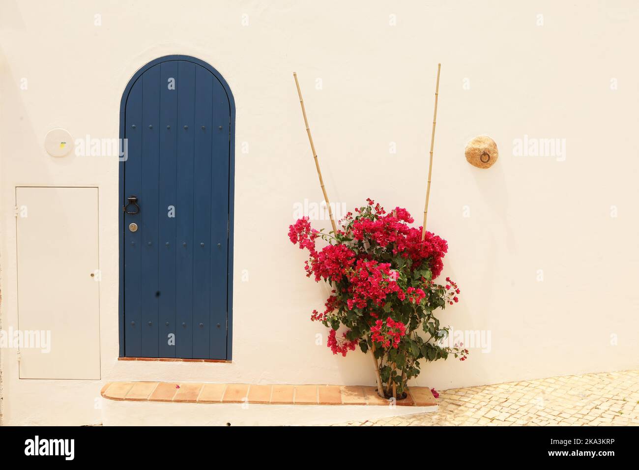 Pink bougainvillea next to a blue door, Lagos, Portugal Stock Photo
