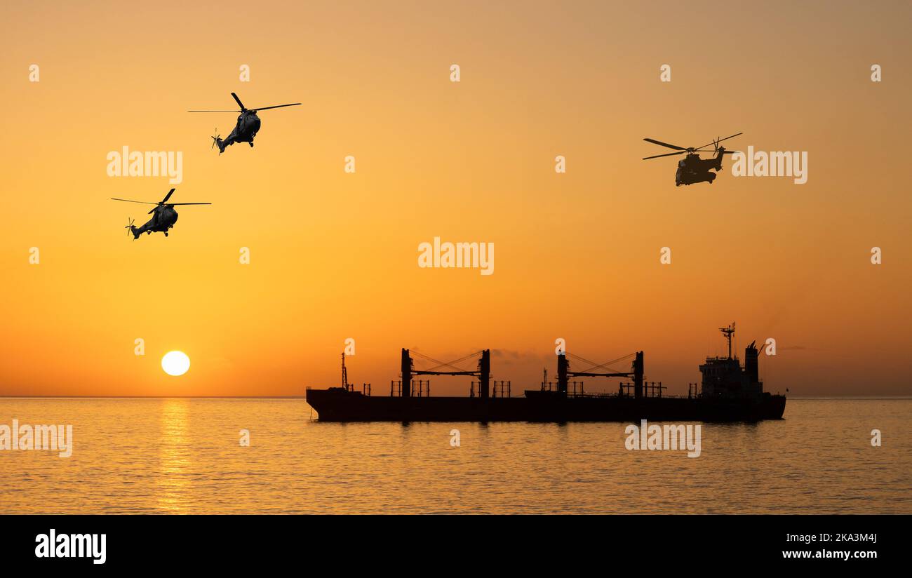 Military helicopters over bulk cargo ship at sunrise. Ukraine grain, wheat, Russia, Russian war, food blockade, shipping, food prices attack.. concept Stock Photo