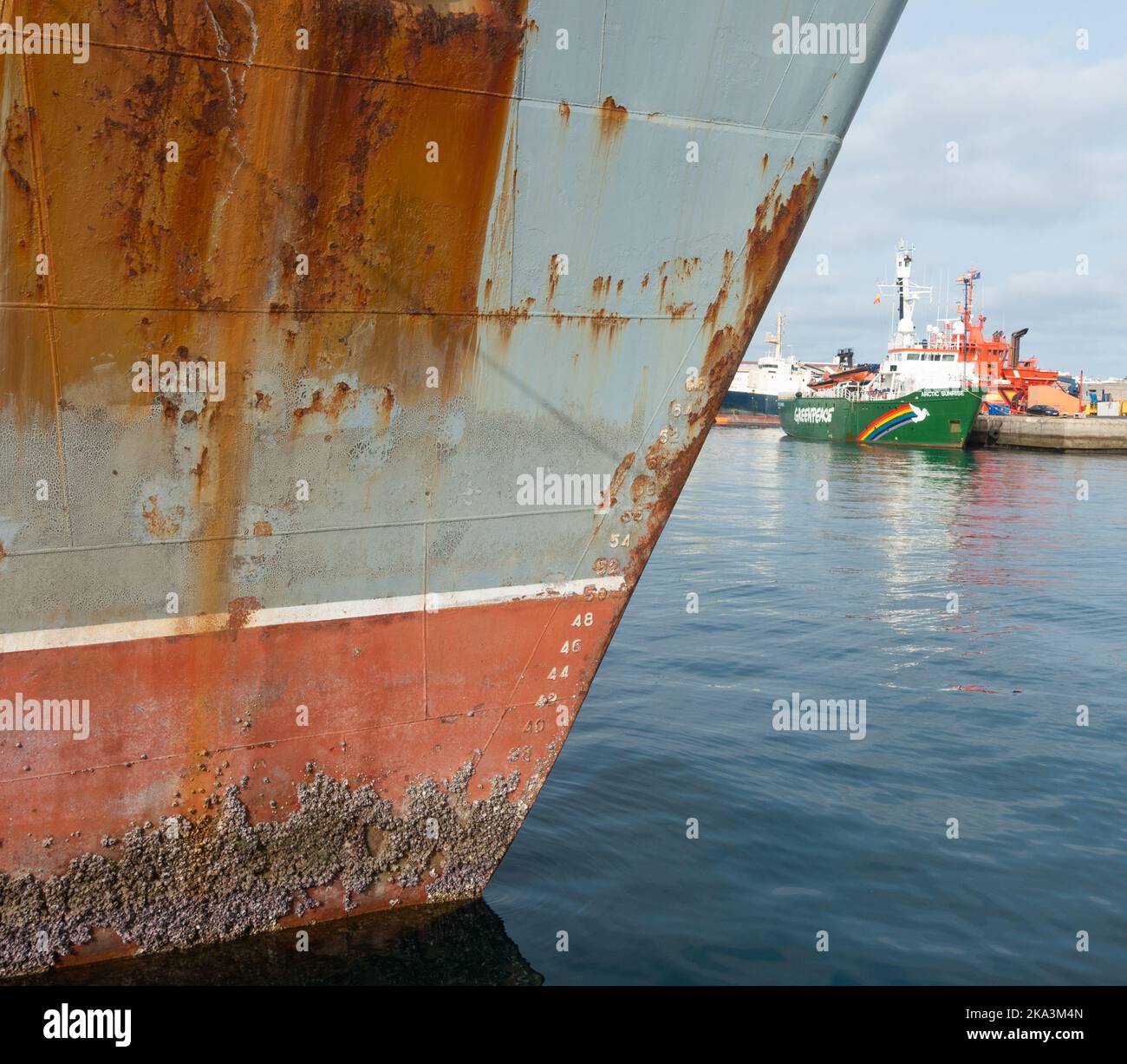 Rusting Russian trawler with Greenpeace ship, Arctic Sunrise in distance. Stock Photo