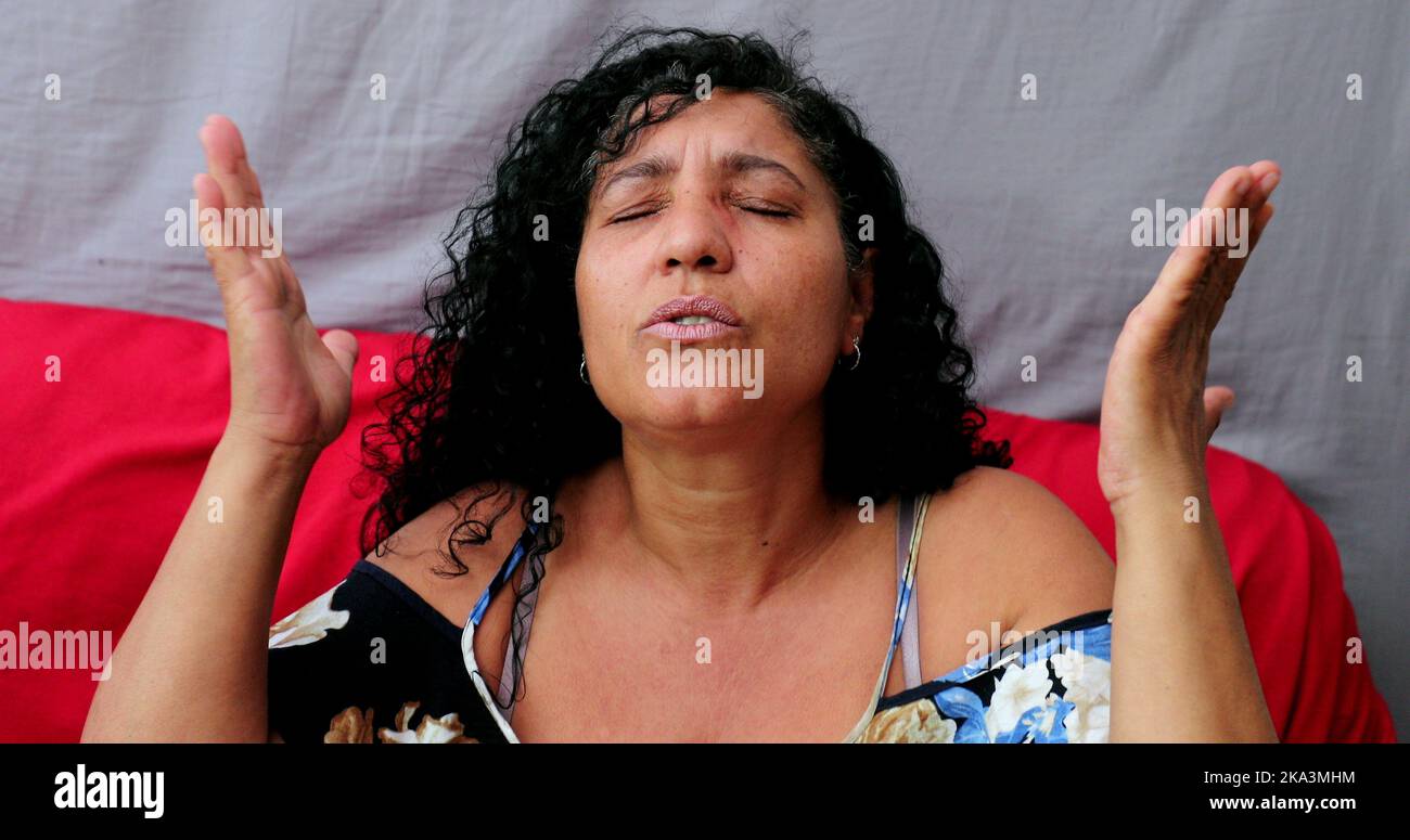 Evangelical Brazilian woman praying to God. Spiritual mature person praising God Stock Photo