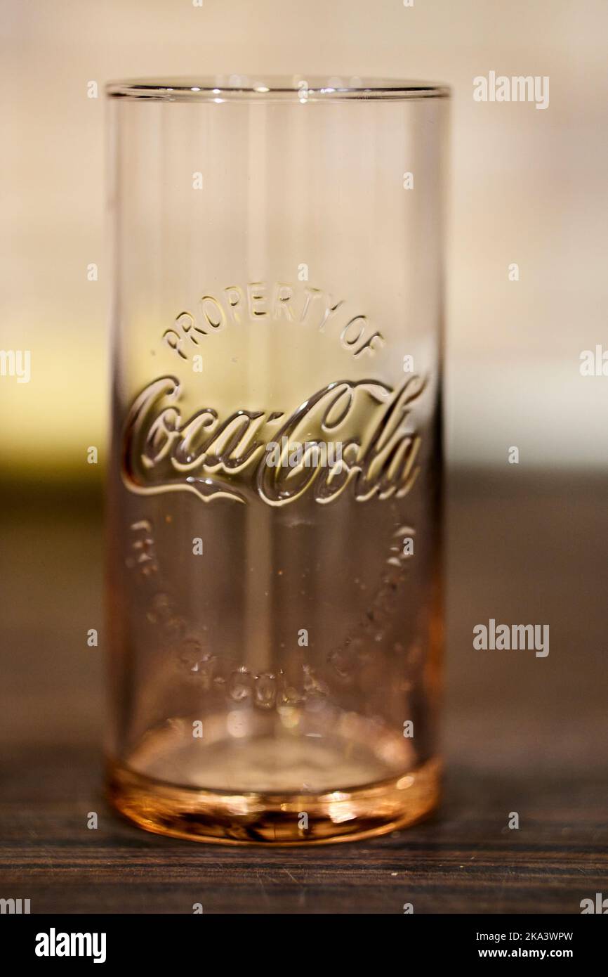 A vertical shot of an empty glass with Coca Cola logo on it placed on a ...